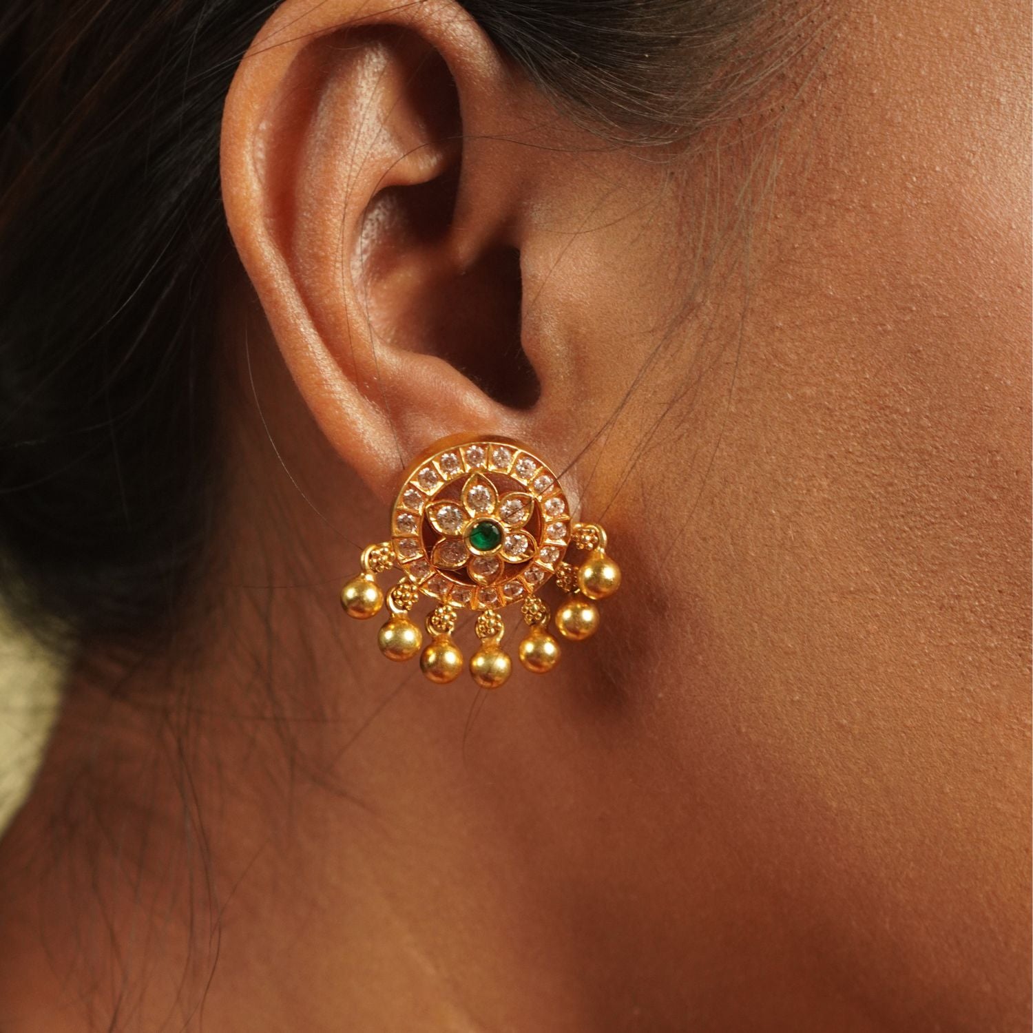 Indulge in luxury with Divasmantra's gold-plated drop earrings, featuring sparkling CZ stones and vibrant green cut stones—a perfect blend of timeless elegance and modern charm.