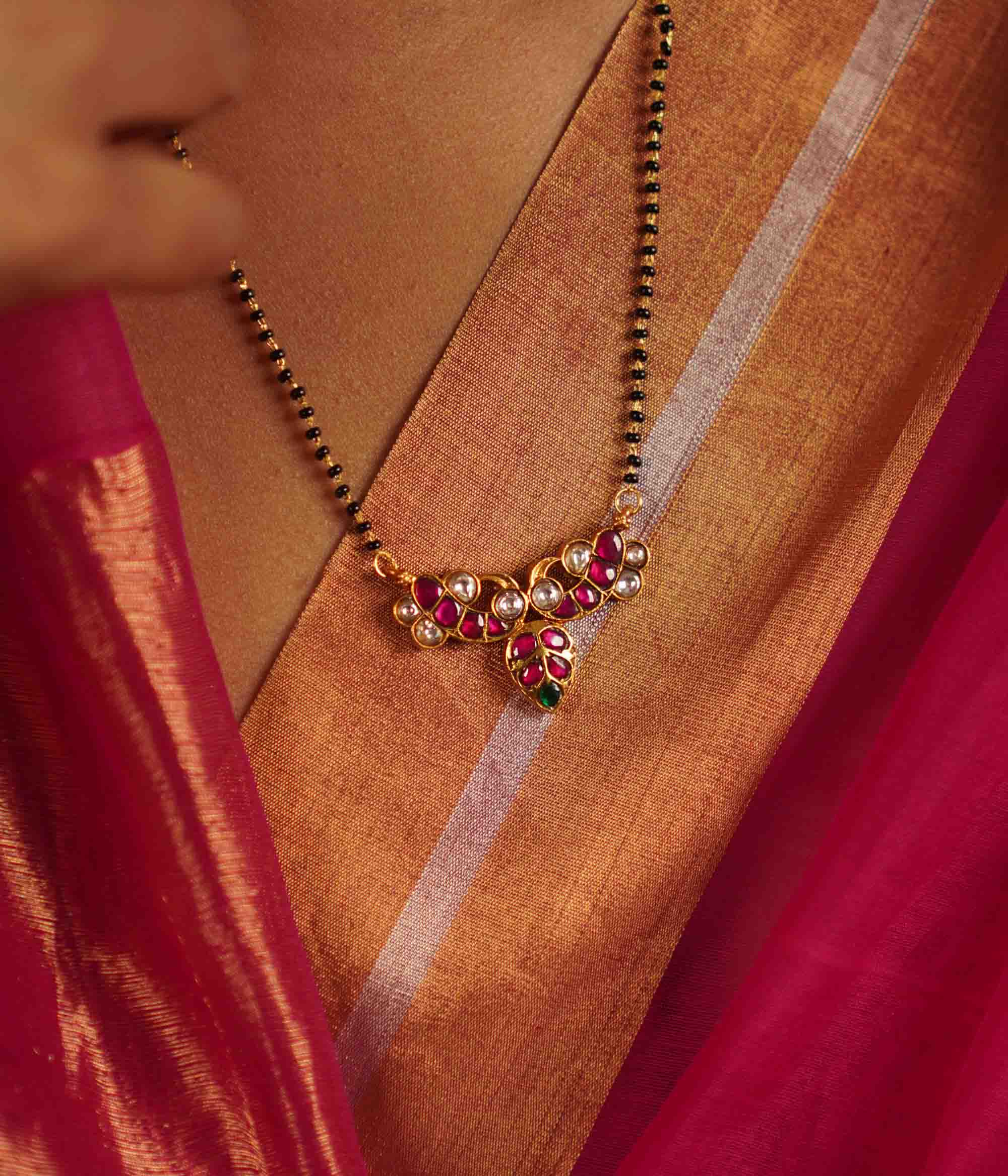 The Alagini Mangalsutra, crafted in gold-plated silver, features vibrant green and pink Kundan stones, beautifully complemented by traditional black beads. A perfect fusion of heritage and elegance, this piece embodies timeless charm with a contemporary touch.