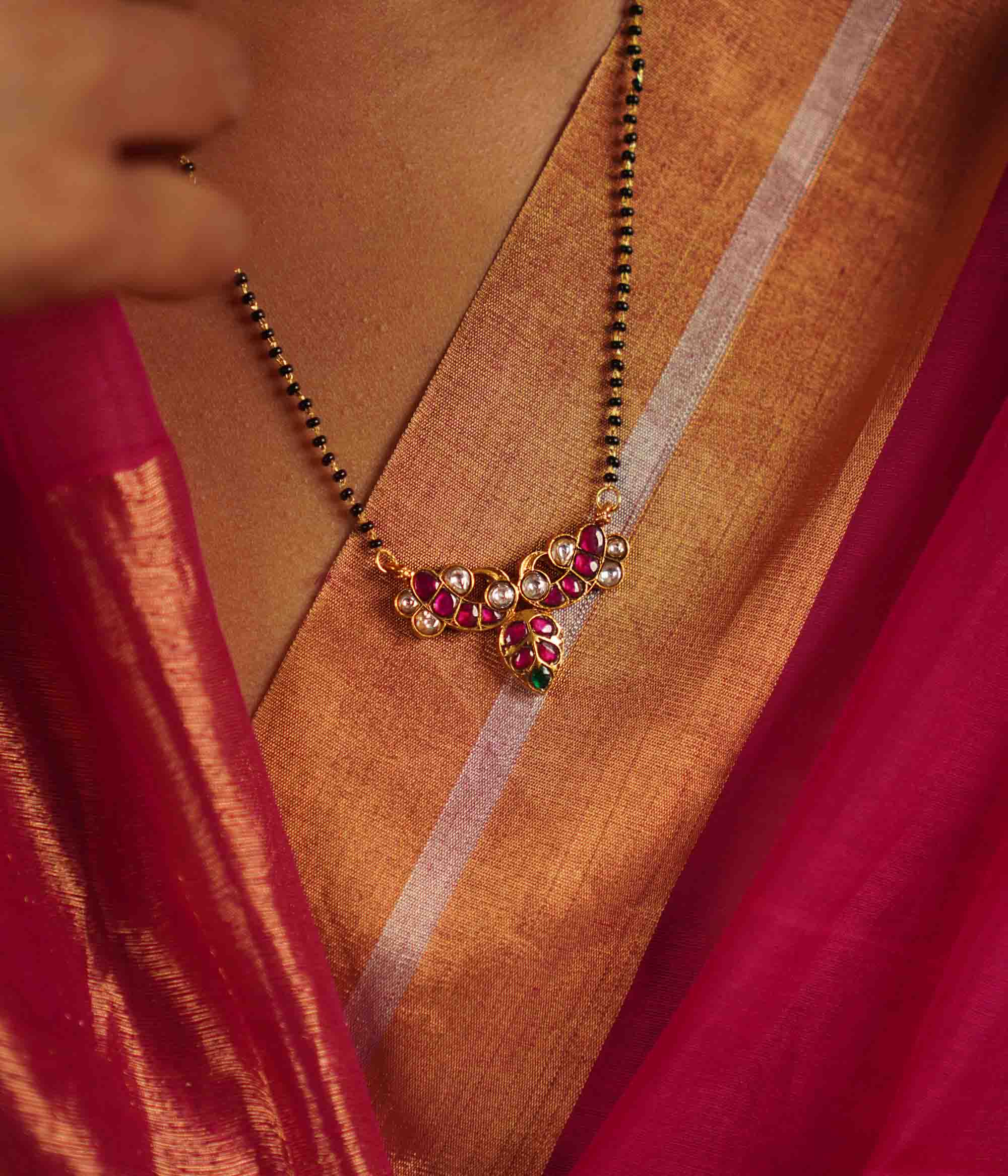 The Alagini Mangalsutra, crafted in gold-plated silver, features vibrant green and pink Kundan stones, beautifully complemented by traditional black beads. A perfect fusion of heritage and elegance, this piece embodies timeless charm with a contemporary touch.