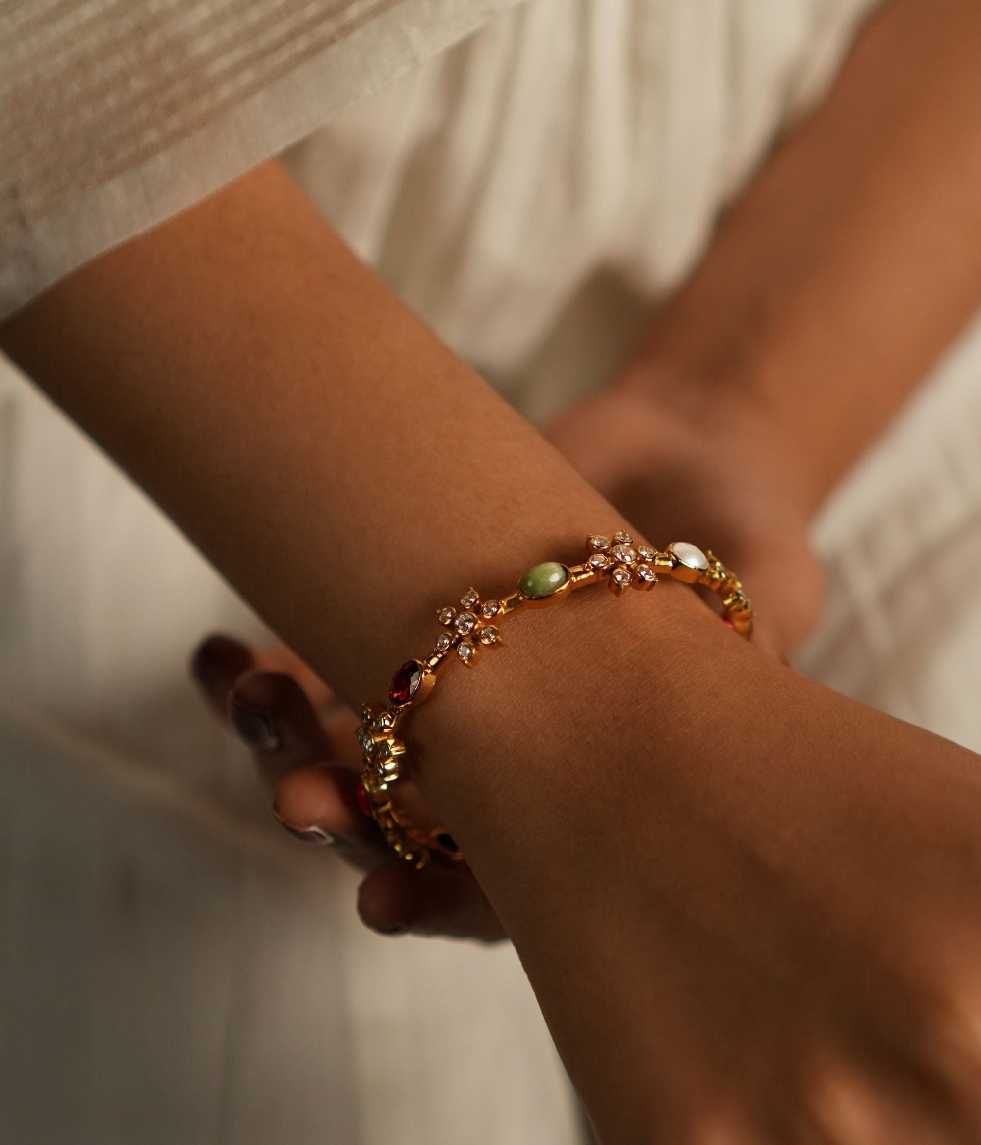 A stunning gold-plated silver bangle featuring exquisite Navratna stones arranged in an elegant floral design. Each vibrant gemstone is gracefully surrounded by shimmering CZ stones, enhancing its brilliance and charm. This intricately crafted piece exudes a timeless appeal, making it a perfect blend of tradition and sophistication.