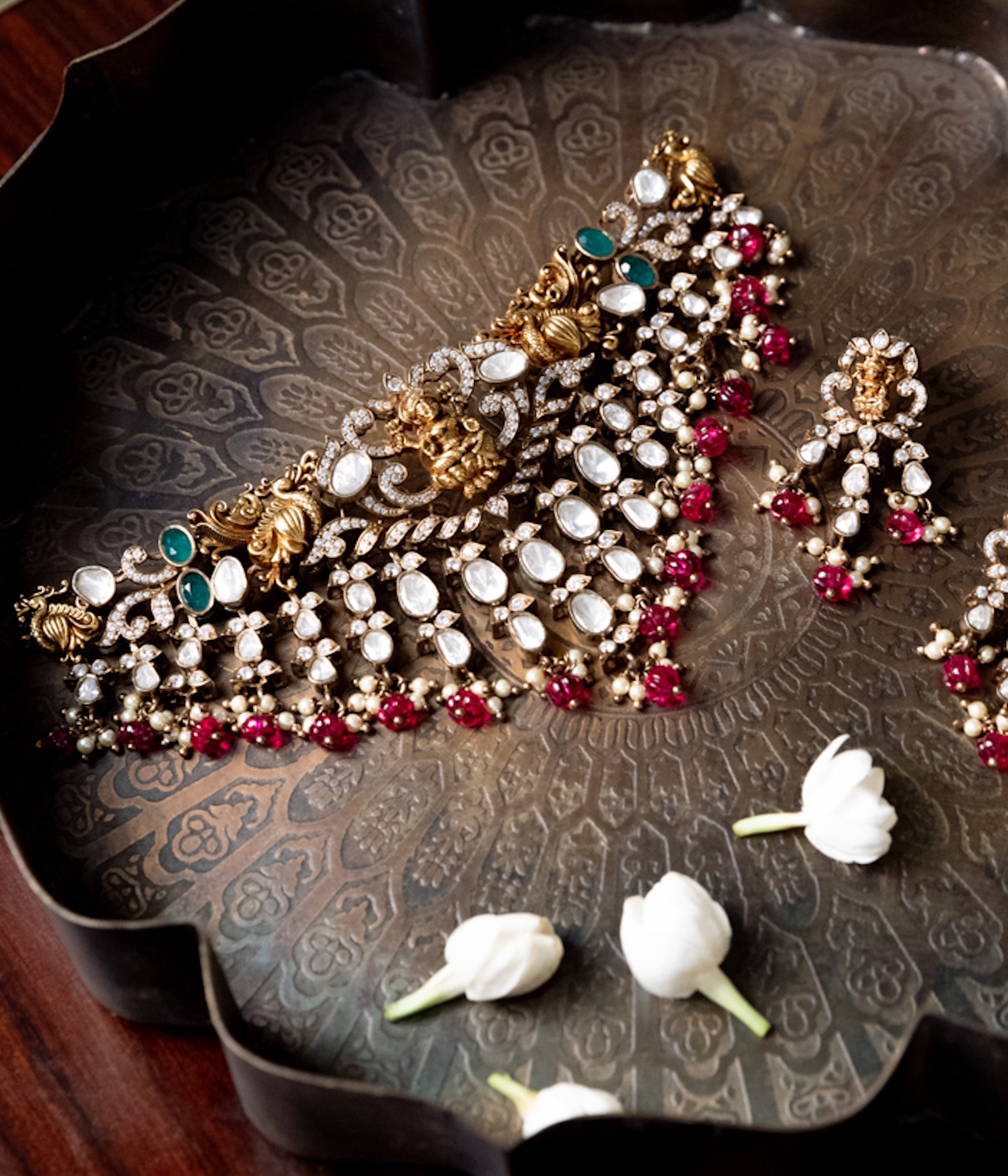 Ornate jewelry set with pearls and red stones on a decorative tray.