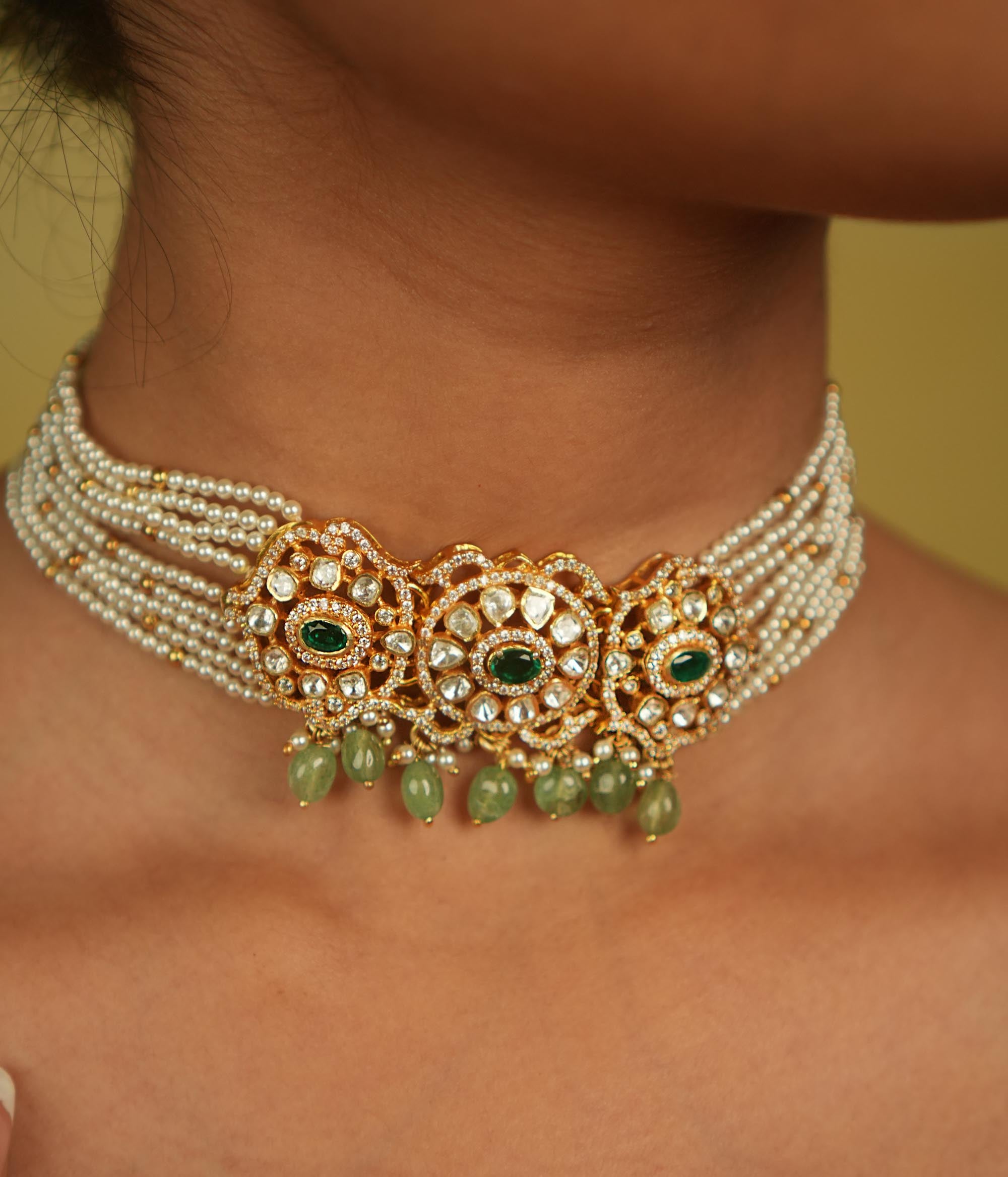 Floral whispers come alive in this exquisite choker, featuring a delicate pearl chain, Moissanite Polki stones, CZ stones, green cut stones, green beads, and pearls. A celestial symphony of opulence and romance, this piece exudes timeless elegance, making it a perfect choice for the discerning connoisseur.