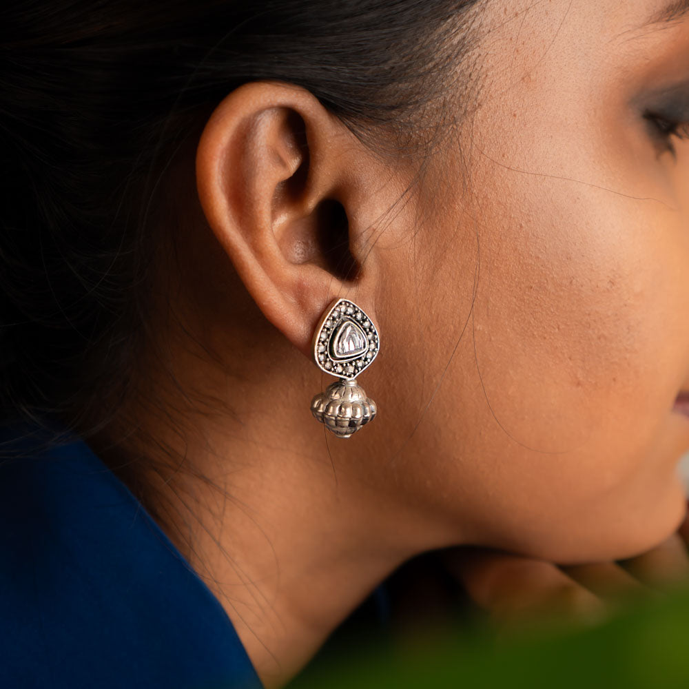These jhumka earrings feature intricately cut polkis at the center, with a gracefully suspended dome, creating a unique and timeless design.