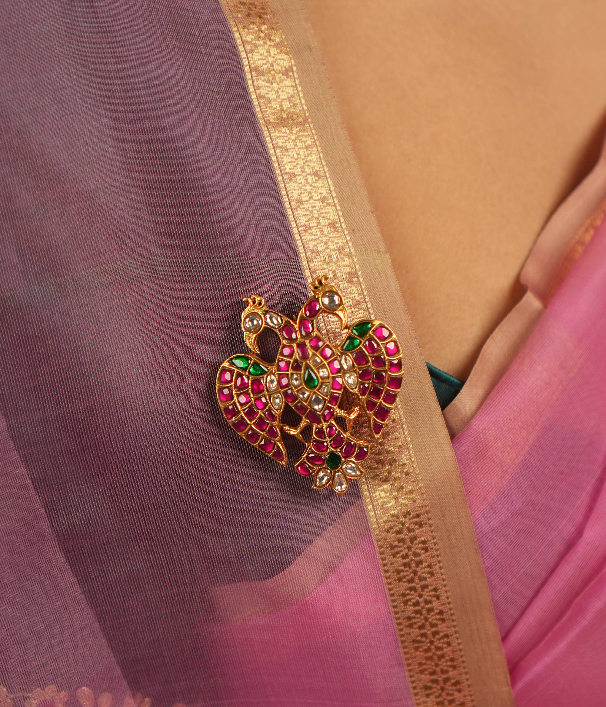 Adorned with red, green, and white Kundan stones, this brooch captivates with its intricate design and radiant hues, exuding timeless charm.