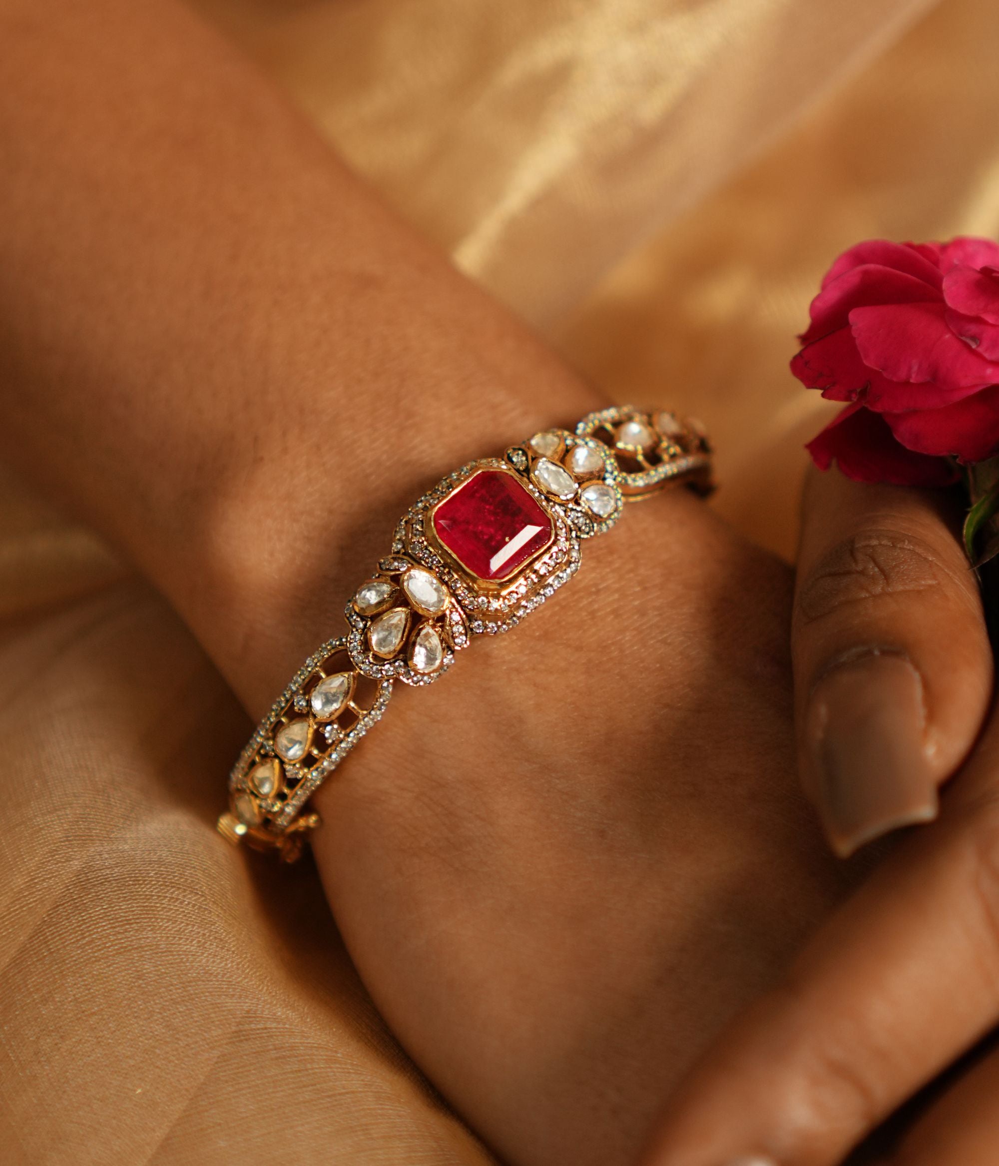 Elegant silver bracelet with gold plating, featuring intricate Moissanite Polki stones, vibrant red gemstones, and sparkling CZ stones, designed to add a touch of sophistication and charm to any occasion.