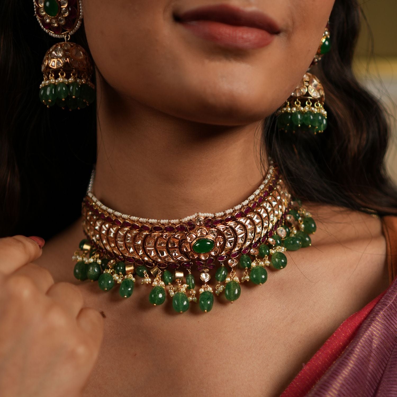 features a stunning 92.5 sterling silver choker with an exquisite gold-plated finish. The choker is adorned with moissanite polkis and vibrant green beads, creating a perfect blend of traditional elegance and modern sophistication. Its intricate craftsmanship and detailed design make it an ideal statement piece for weddings, festive occasions