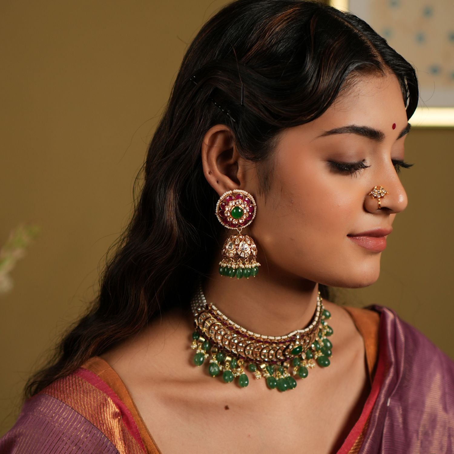 This image showcases an exquisite pair of Moissanite Polki Jhumkas crafted from 92.5 sterling silver and finished with a luxurious gold plating. The earrings feature a vibrant combination of deep red and green stones, with intricate Polki work that exudes traditional elegance.