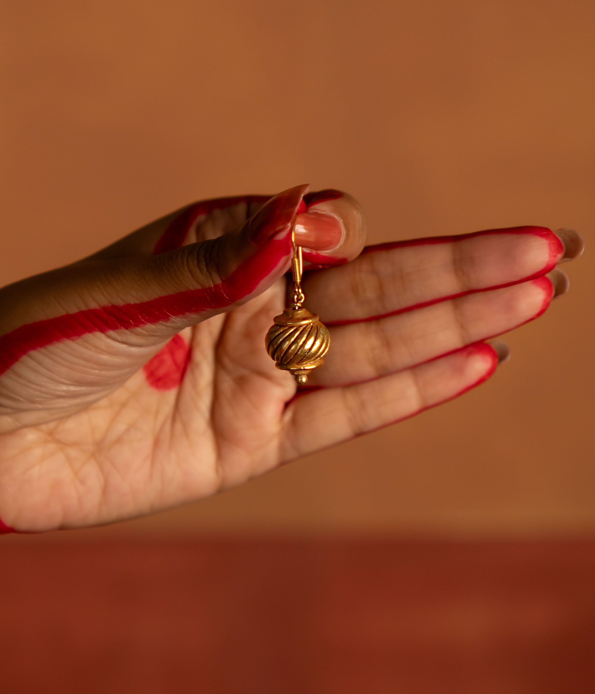 Gold-plated silver hook earrings, inspired by Hanuman's gada, symbolize strength and elegance. With a vintage Kolhapuri tribal touch, this minimalist piece radiates quiet confidence and divine courage.