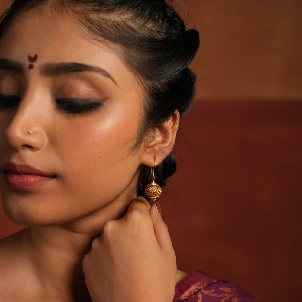 Gold-plated silver hook earrings, inspired by Hanuman's gada, symbolize strength and elegance. With a vintage Kolhapuri tribal touch, this minimalist piece radiates quiet confidence and divine courage.