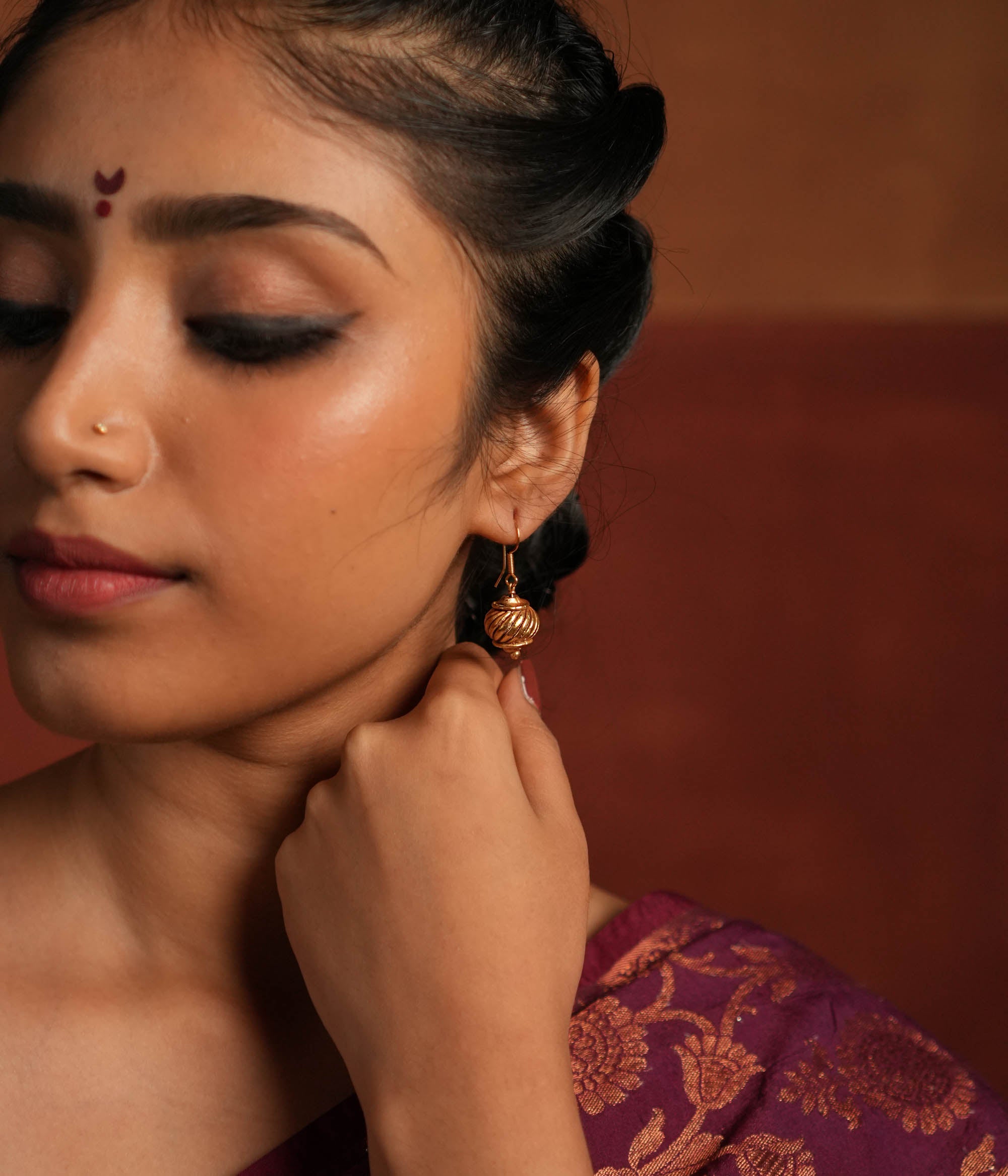 Gold-plated silver hook earrings, inspired by Hanuman's gada, symbolize strength and elegance. With a vintage Kolhapuri tribal touch, this minimalist piece radiates quiet confidence and divine courage.