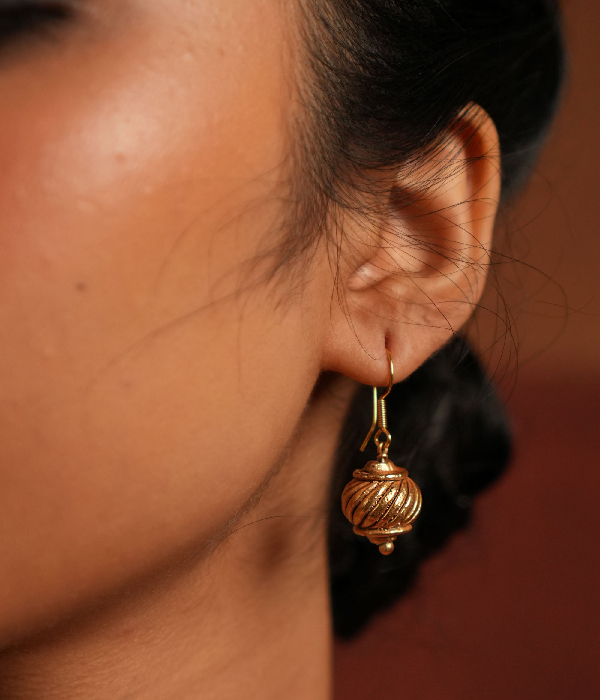Gold-plated silver hook earrings, inspired by Hanuman's gada, symbolize strength and elegance. With a vintage Kolhapuri tribal touch, this minimalist piece radiates quiet confidence and divine courage.