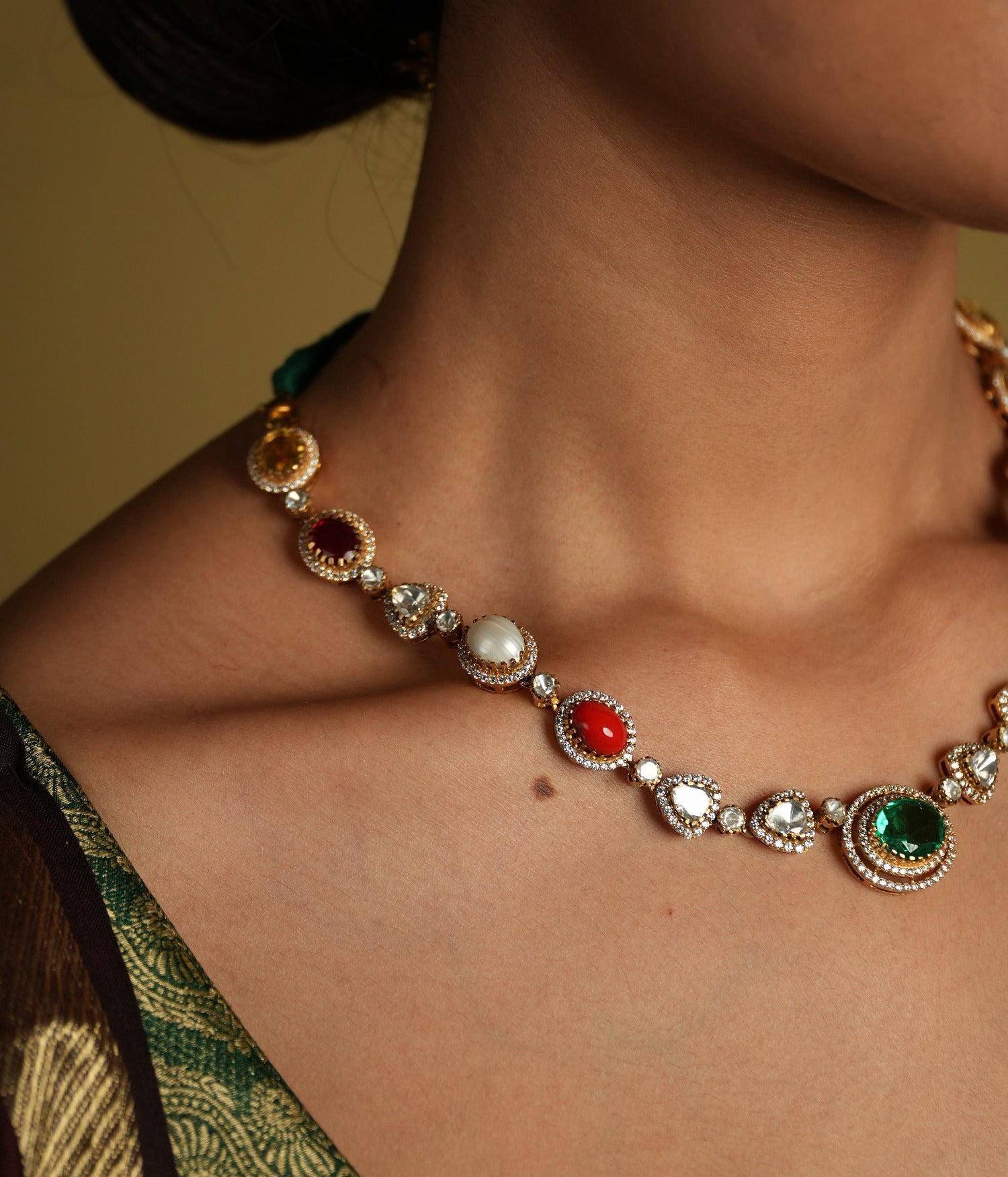 This elegant 92.5 sterling silver necklace is beautifully gold-plated and features a classic Navratna design. Adorned with nine vibrant gemstones, including emerald, ruby, sapphire, coral, and more, each stone represents celestial significance and brings a pop of color to your ensemble