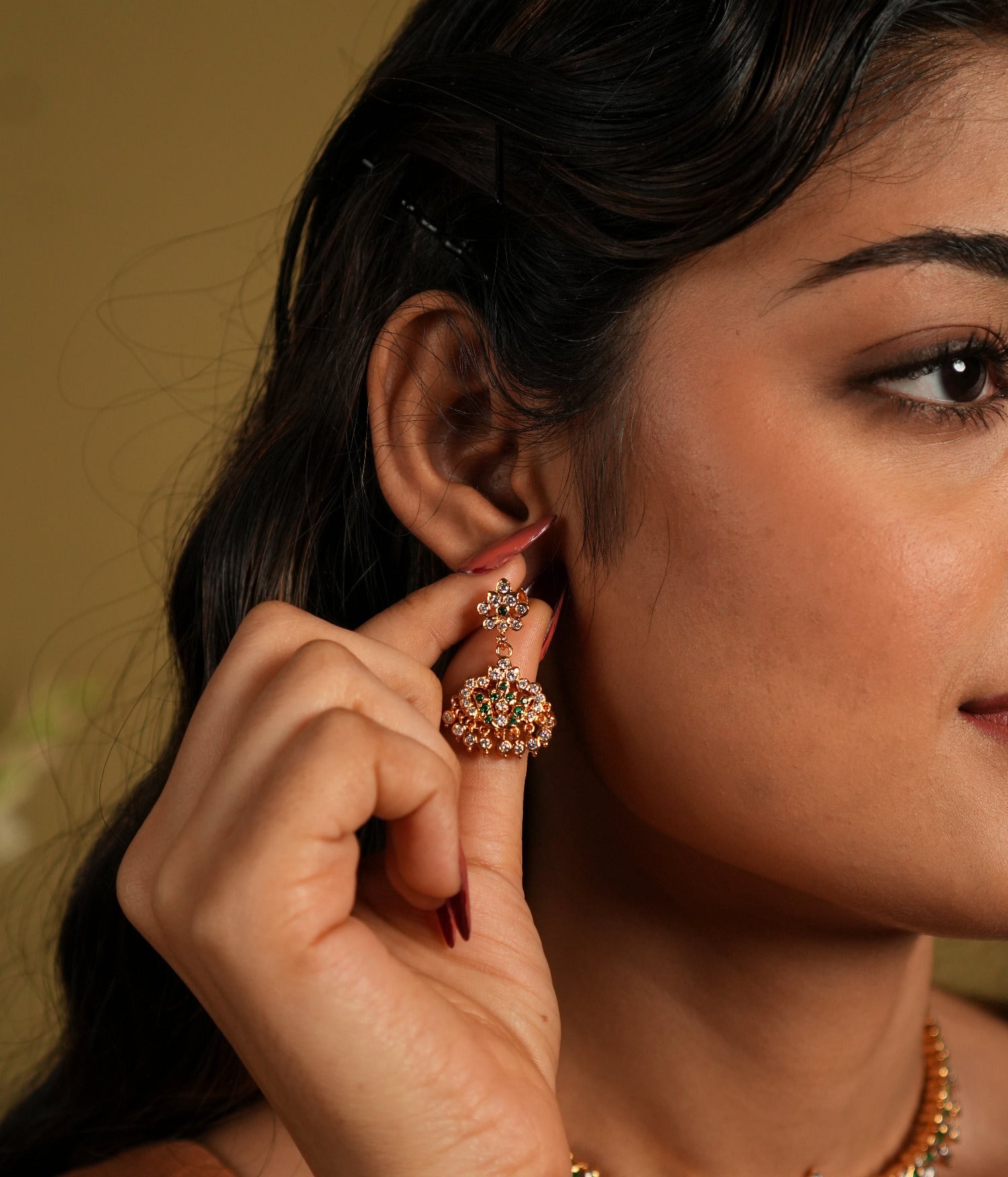 showcasing jewelry that appears to be made of 92.5 silver and adorned with Swarovski stones. The jewelry, including earrings and a necklace, seems to have a gold-plated finish, giving it a rich, elegant look.