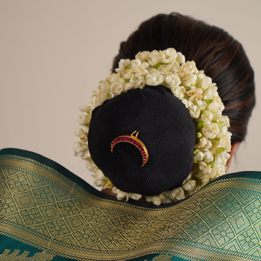 The Chandra hairpin, designed in an antique gold-plated silver finish, showcases a graceful moon-shaped silhouette adorned with radiant red kundan stones. A perfect fusion of heritage and contemporary elegance, each piece is meticulously handcrafted with care.