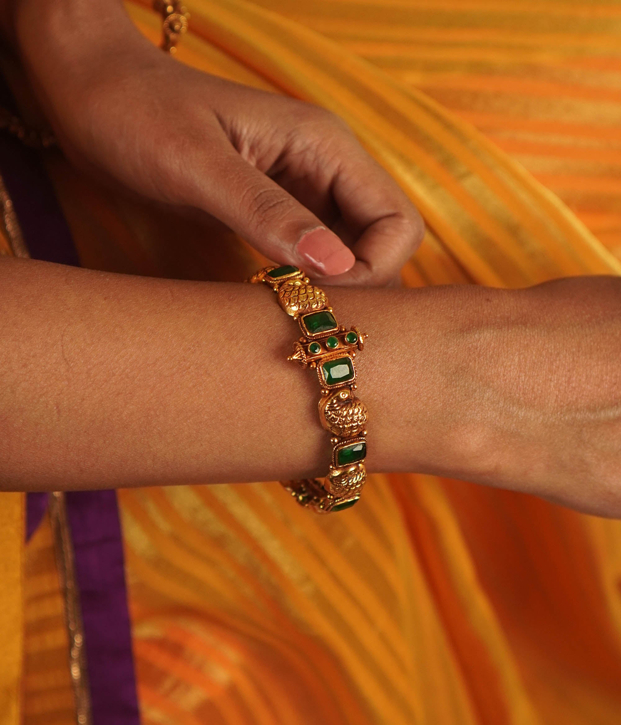 Sleek, handcrafted gold-plated silver bangle channel-set with brilliant-cut emerald green stones.
A stunning silhouette.