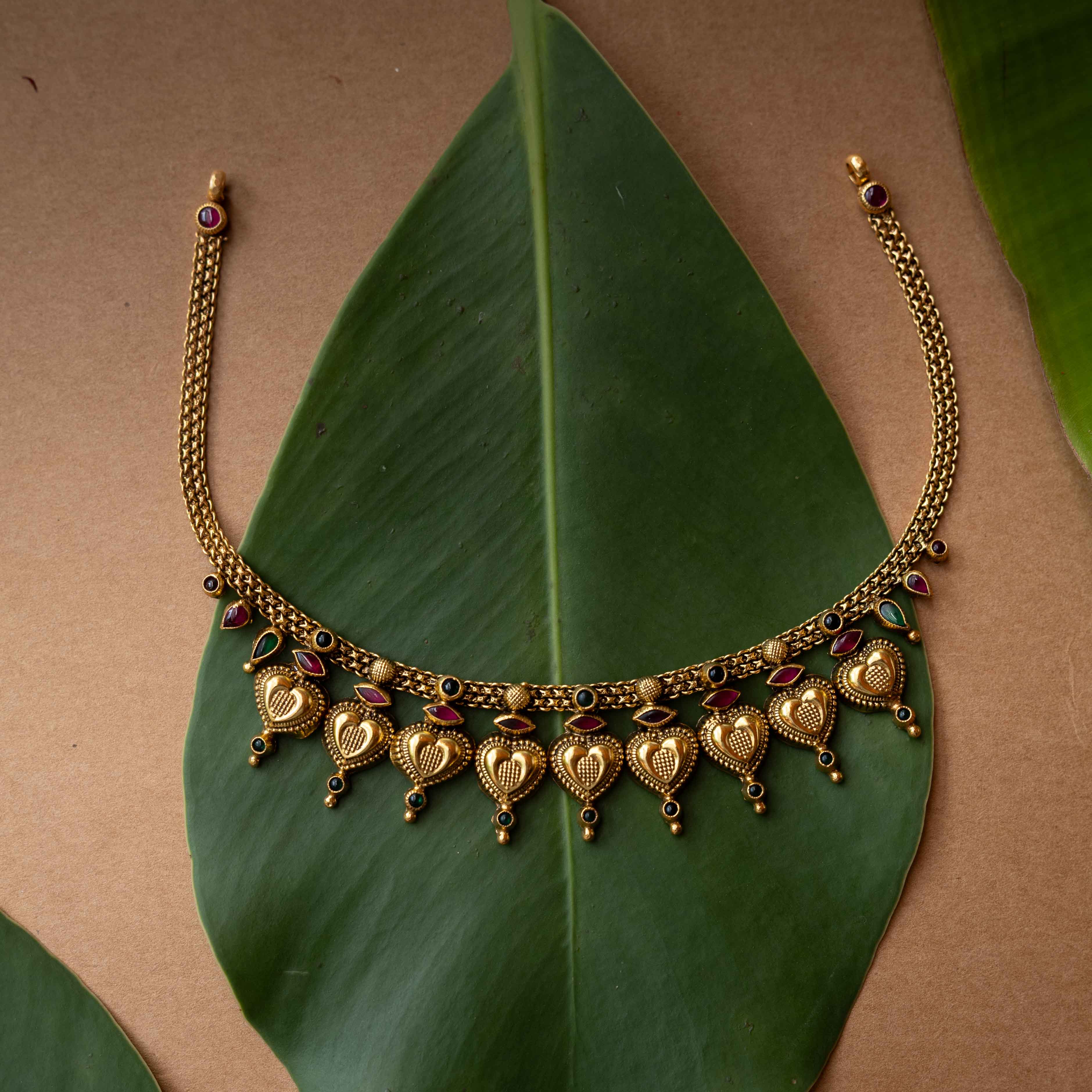Antique gold temple necklace with heart-shaped motifs and ruby-green accents from Temple Collection.