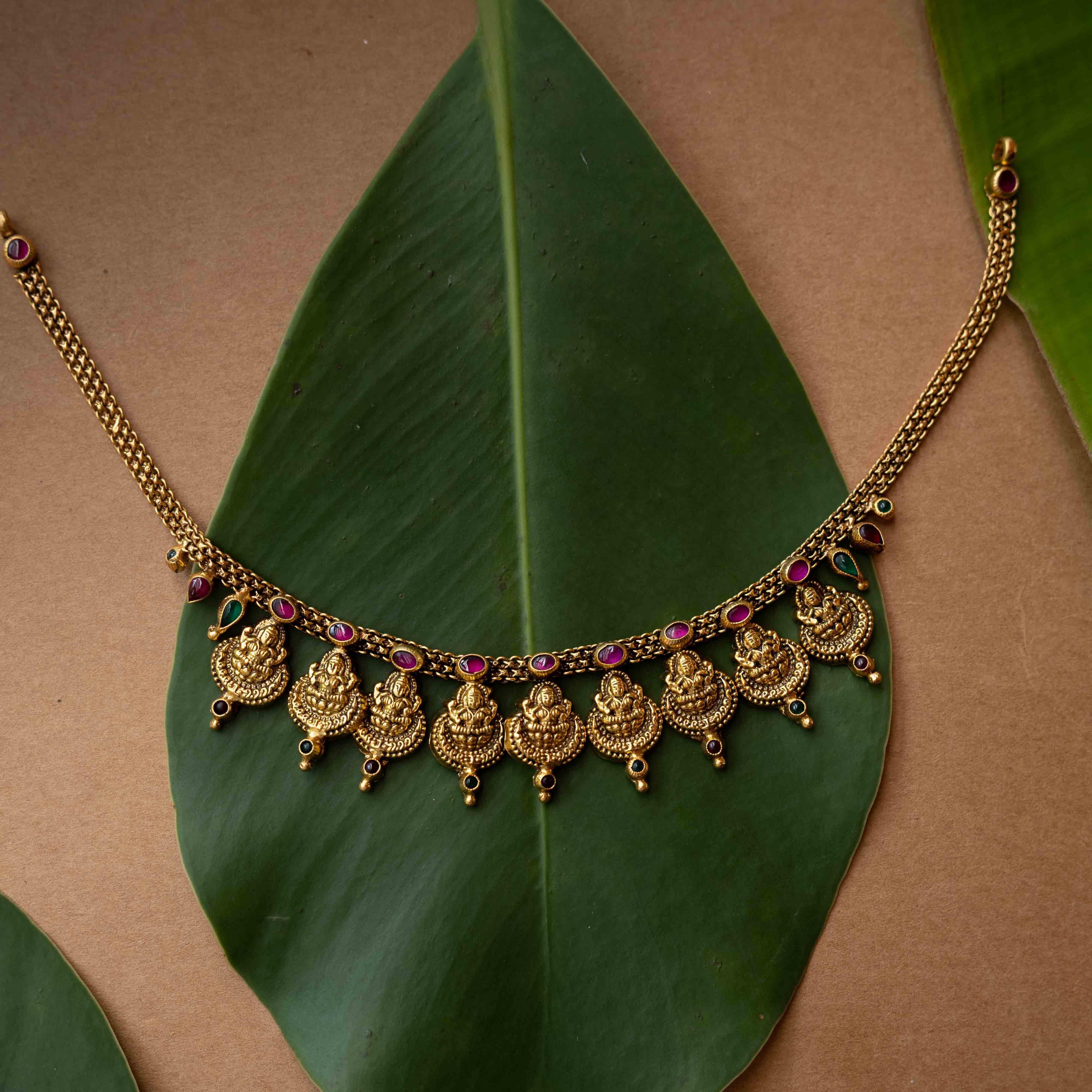 Antique gold temple necklace with multiple Lakshmi motifs and ruby-green accents from Temple Collection.