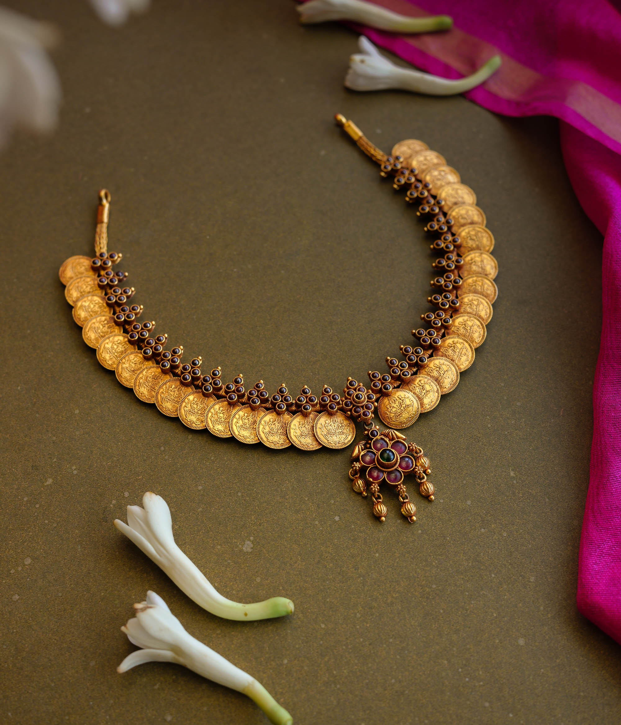 Gold coin motif necklace with red and green stones from Temple Collection.