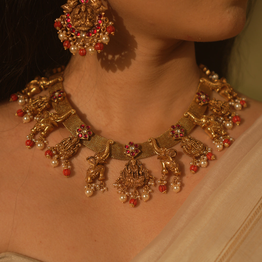Temple collection Aamal Necklace featuring Goddess Lakshmi, elephant motifs, pink Kundan stones, pearls, and coral beads.
