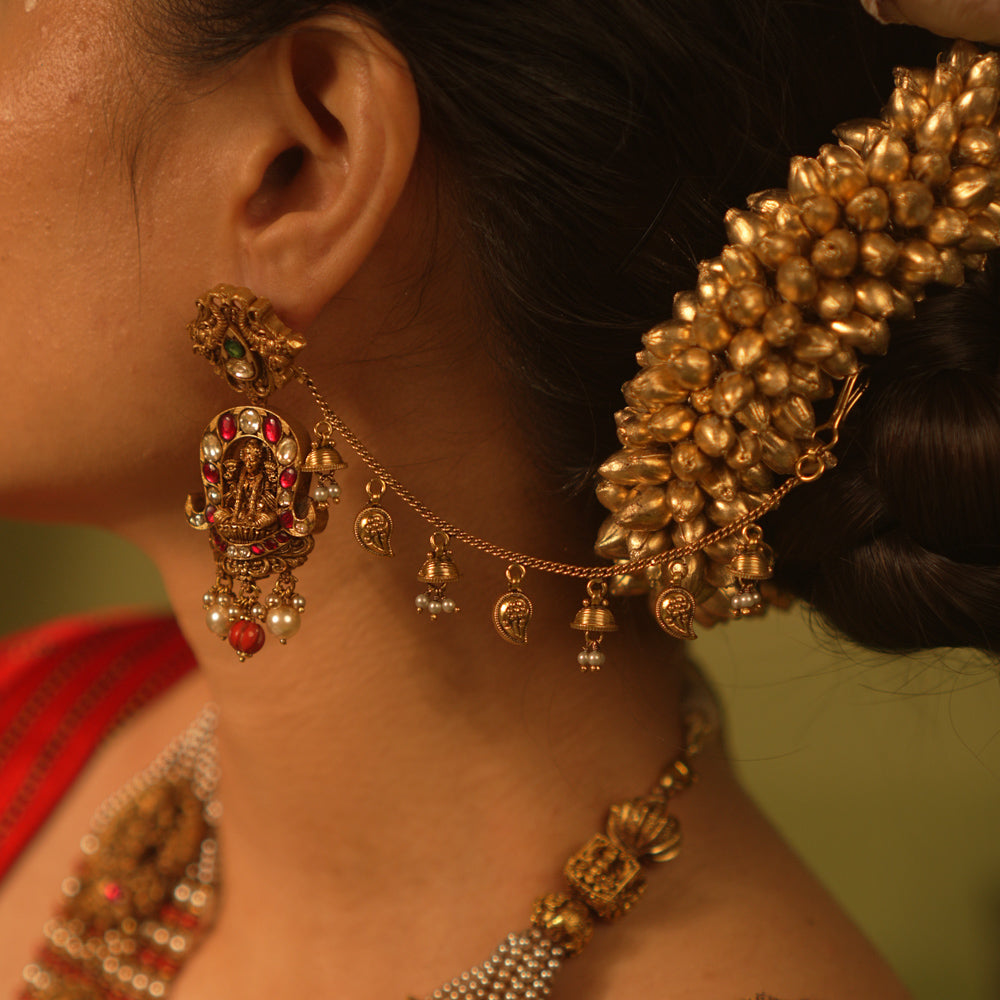 Traditional temple ear chain with Lakshmi motif, red and green Kundan stones, coral beads, and pearl danglers.