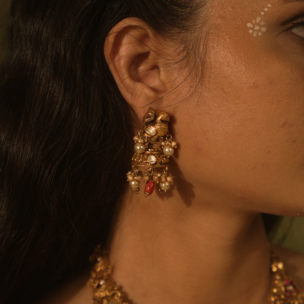 Temple jhumkas with peacock motifs, coral details, and Basra pearls—blending tradition with vibrant beauty.