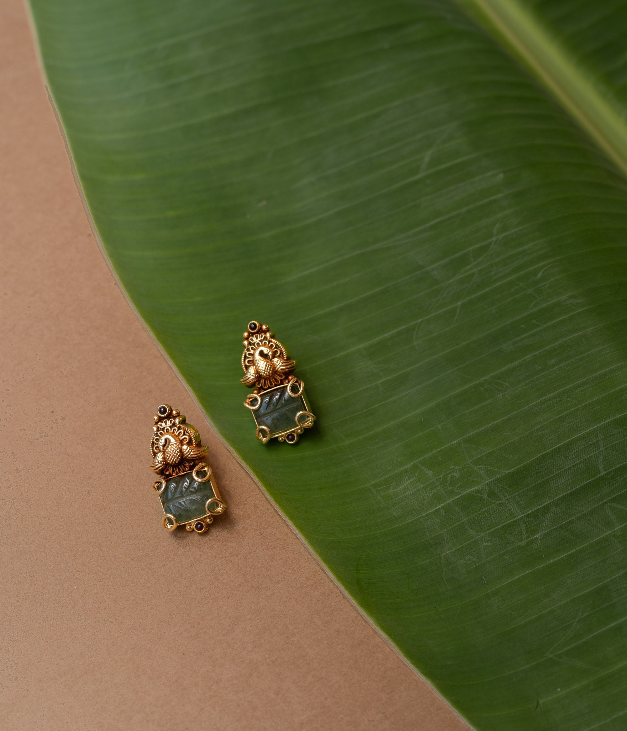 Temple-style gold earrings with peacock design and green onyx stone, from the Temple Collection.
