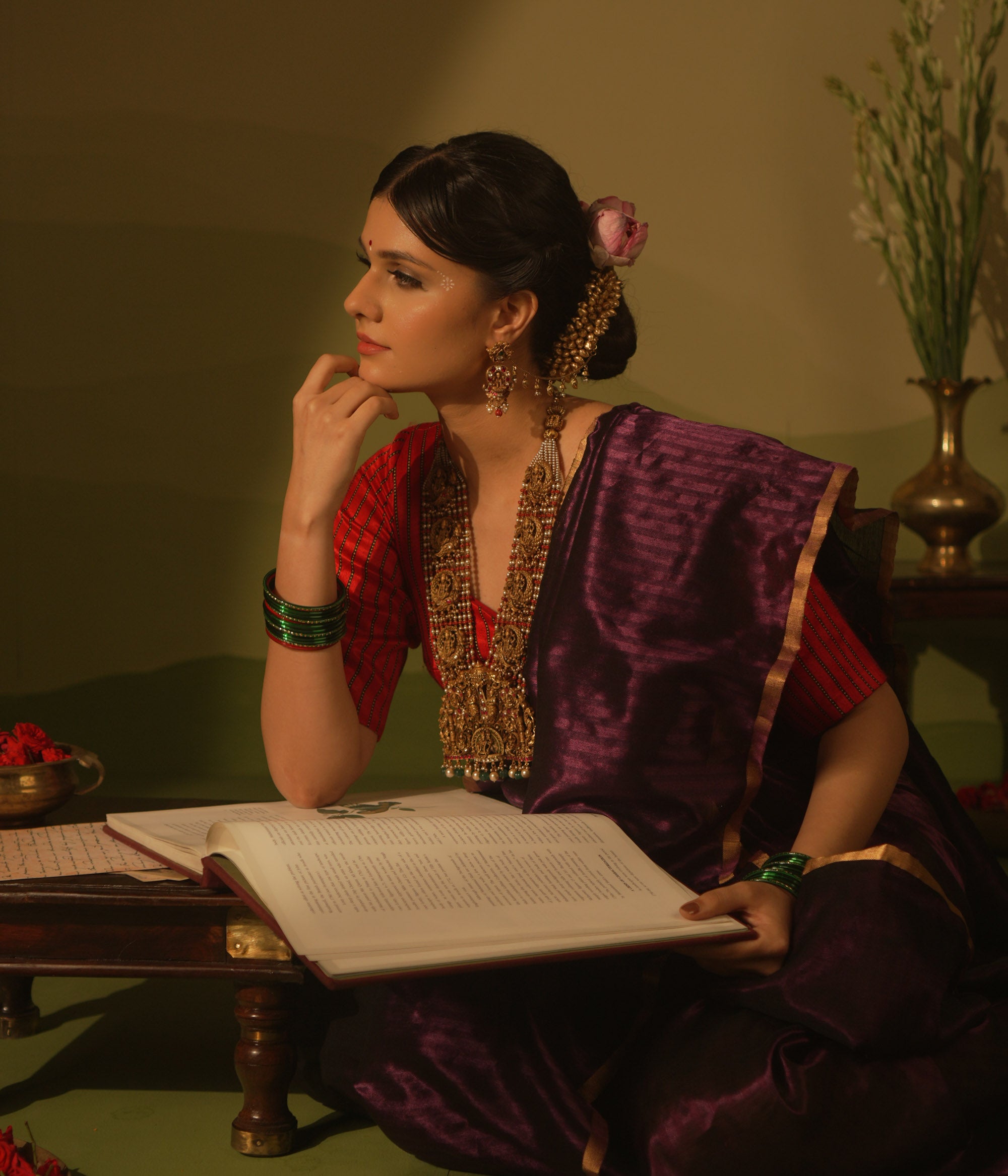 Temple necklace featuring goddess Lakshmi motifs, red and white Kundan stones, green beads, and pearls for traditional bridal wear.