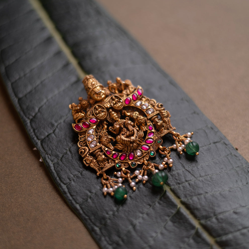 Temple pendant featuring Goddess Lakshmi with Garuda, detailed with red and white kundan and green beads.