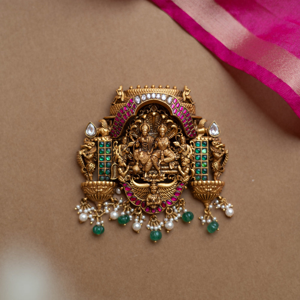 Antique gold temple pendant featuring deities, red, white, and green kundan, green beads, and pearls.