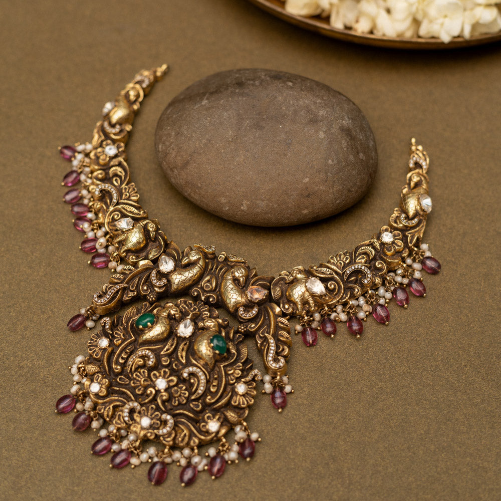 Antique gold-finished 92.5 sterling silver necklace with intricately handcrafted peacocks adorned with vibrant gemstones and pearl drops, embodying regal elegance and traditional opulence.