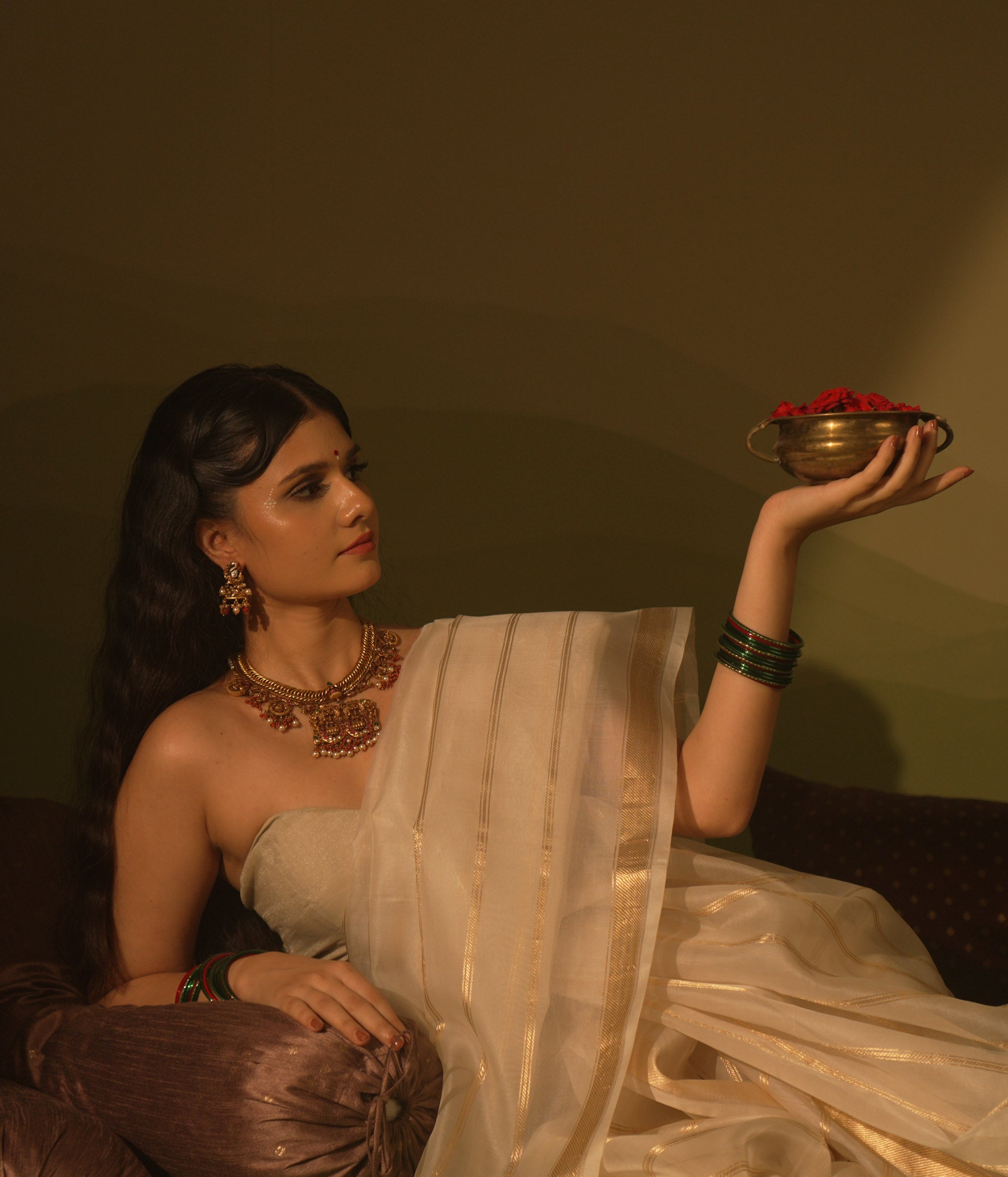 Gold temple necklace with pink kundan peacock pendants, carved deity, pearls, and coral.