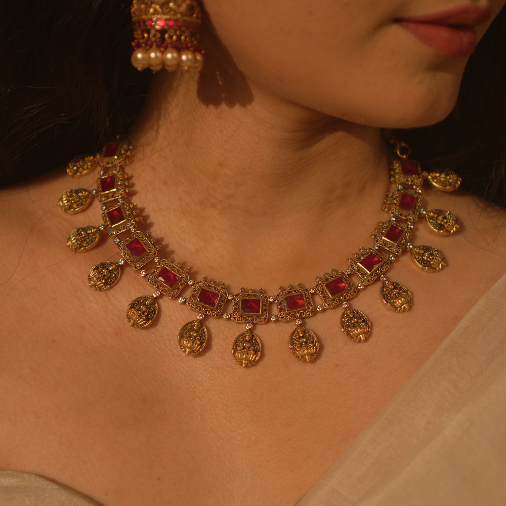 Temple-inspired necklace with red gemstones and Lakshmi motifs, blending divine elegance and traditional craftsmanship.