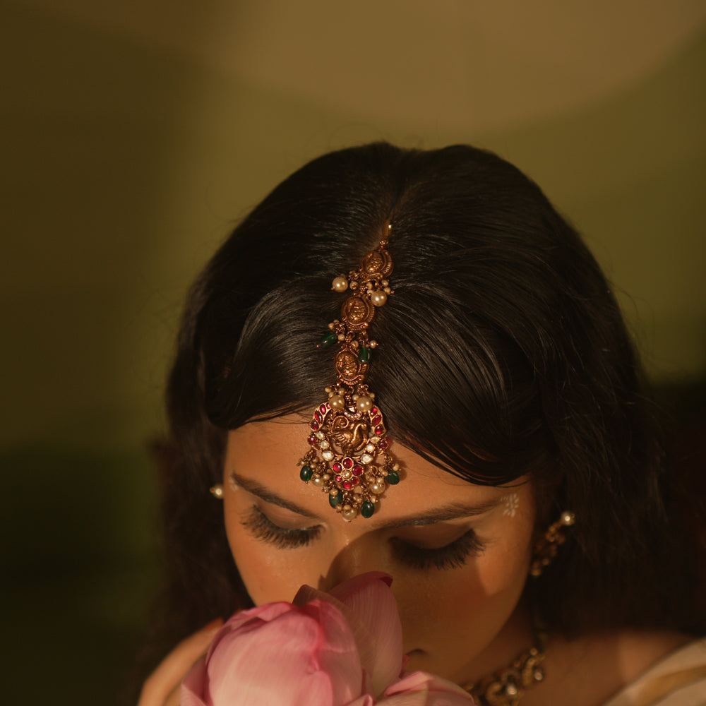 Temple collection maangtika featuring peacock and floral designs with Kundan stones, pearls, and emerald beads for traditional elegance.