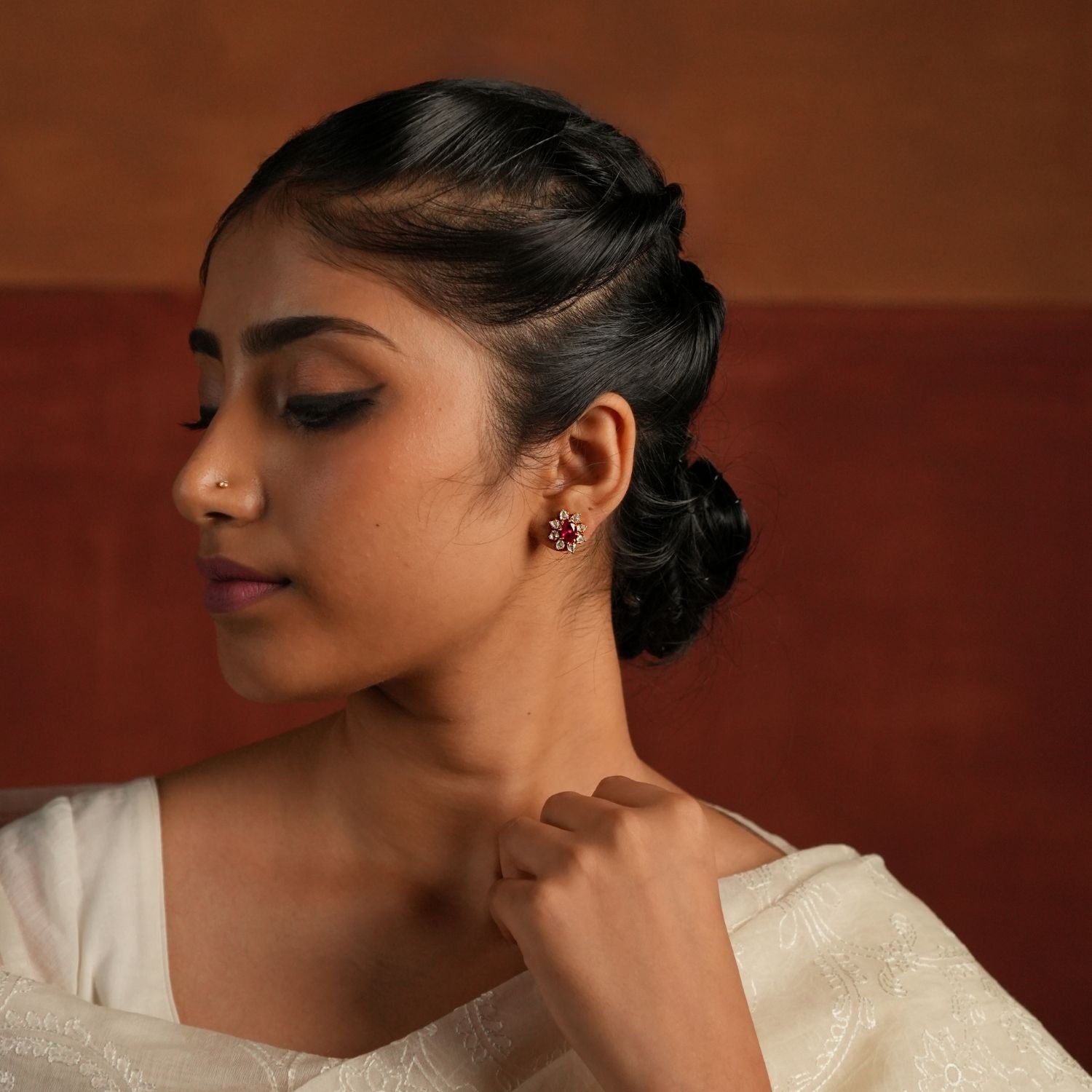 Elegant gold-plated silver stud earrings in a charming floral design, featuring a vibrant pink tourmaline stone at the center. The delicate petals are adorned with shimmering CZ stones, enhancing the floral look with brilliance. Perfect for adding a touch of grace to traditional attire, these studs exude timeless elegance.