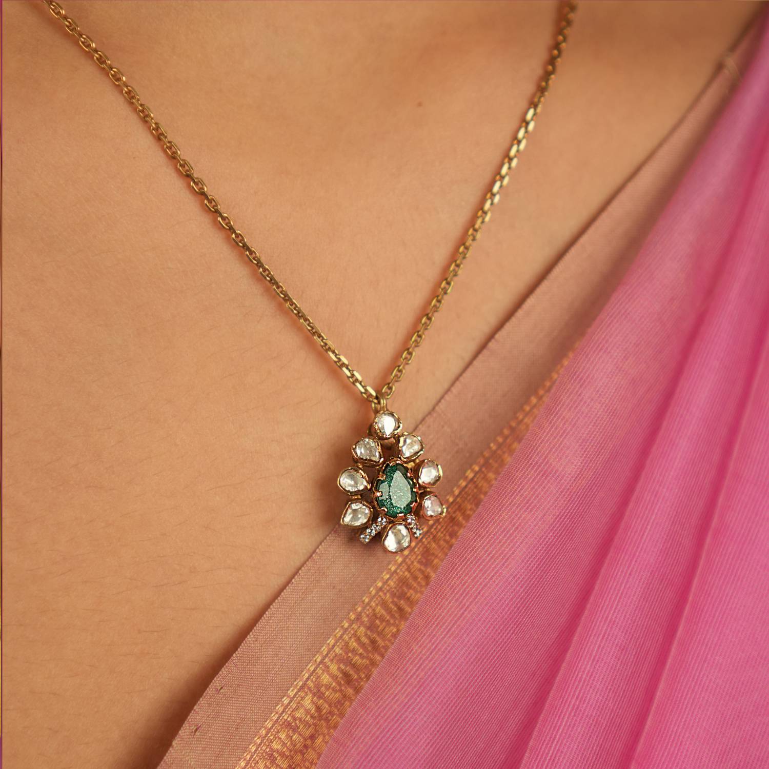 A teardrop Polki pendant, adorned with shimmering Moissanite and a captivating green gemstone, exudes vintage charm and timeless grace.