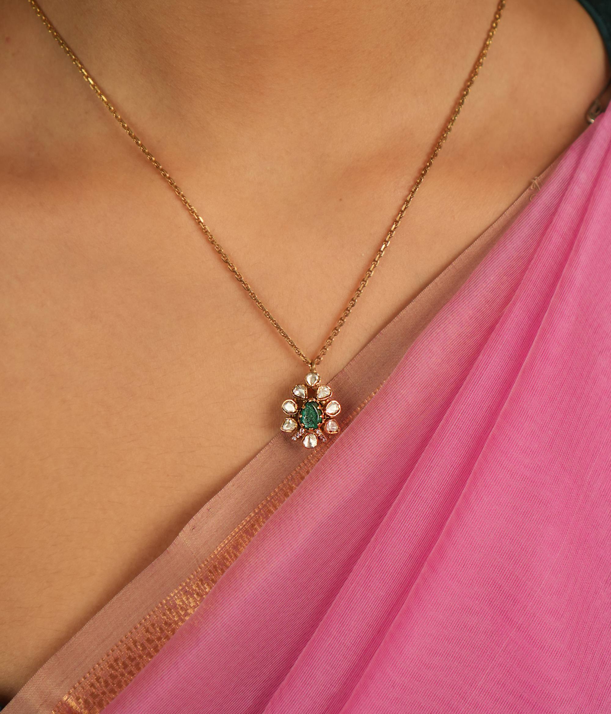 A teardrop Polki pendant, adorned with shimmering Moissanite and a captivating green gemstone, exudes vintage charm and timeless grace.