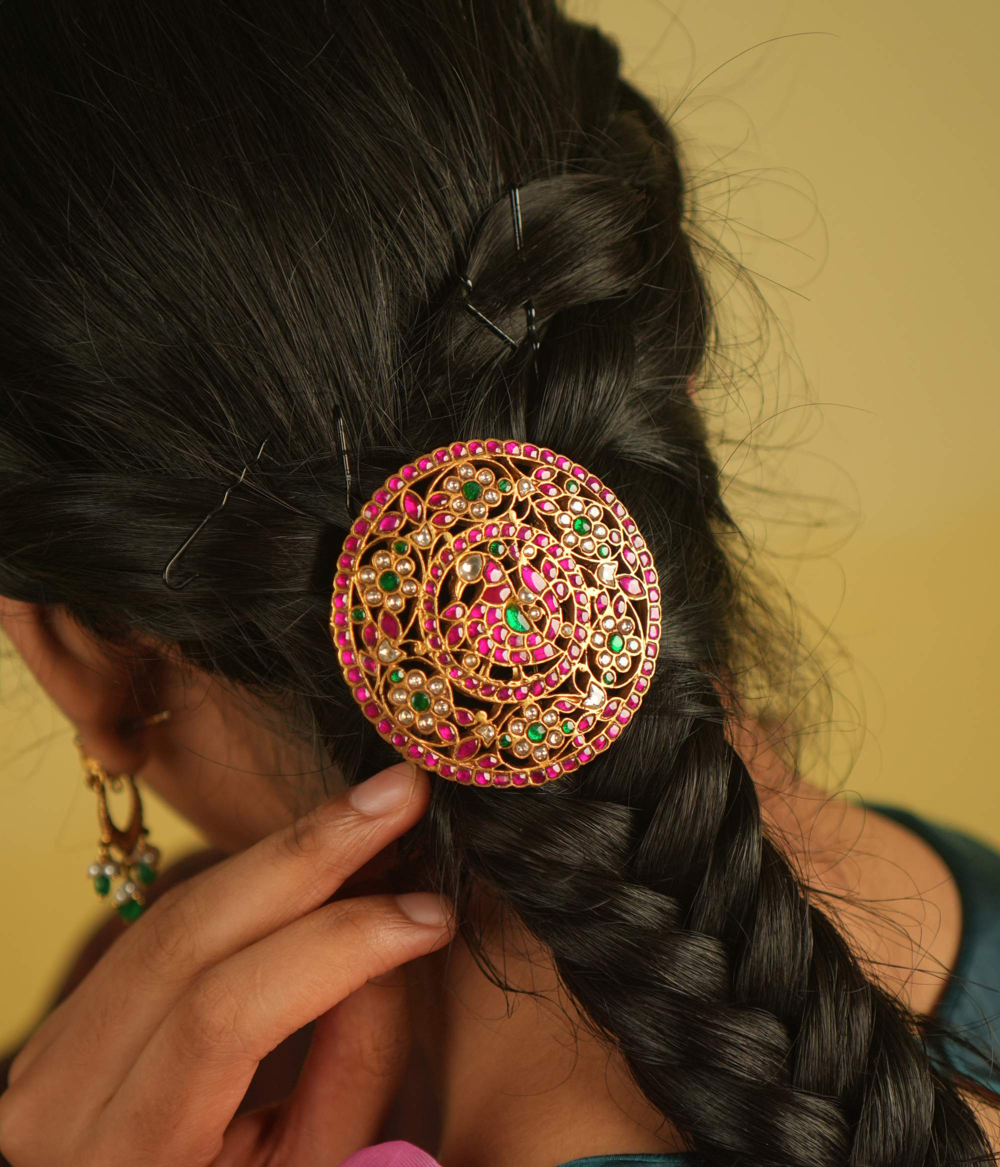 A hairpin adorned with red, green, and white Kundan stones, reflecting nature's brilliance—an ode to the peacock's grandeur and blossoming flowers.
