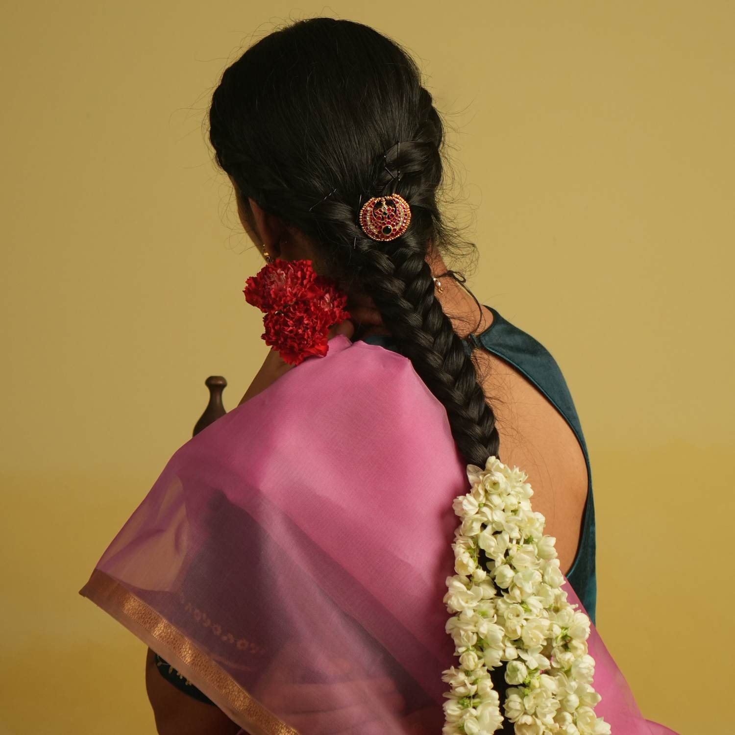 A crescent moon hairpin, embellished with soft pink Kundan and a captivating emerald at its heart, exudes celestial charm and timeless elegance.
