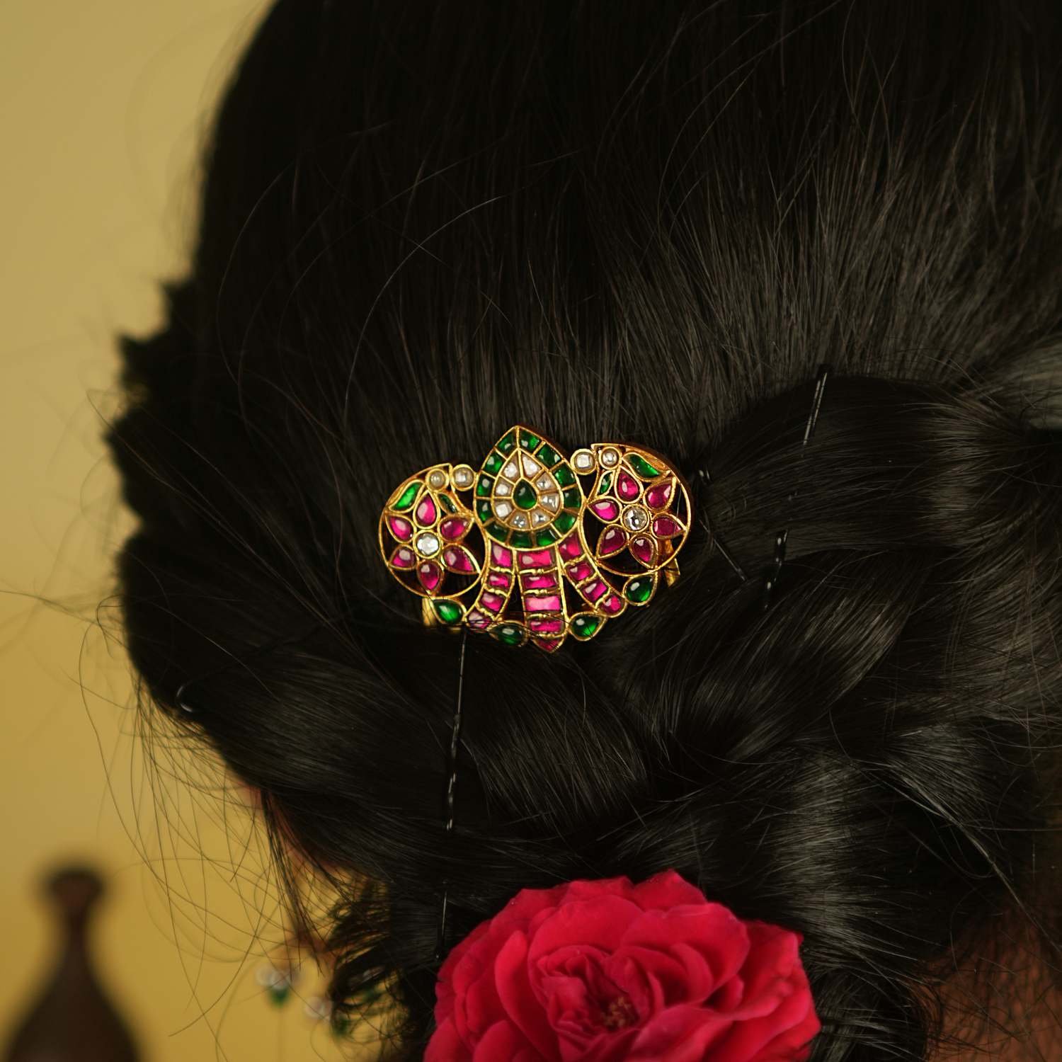 A sleek hairpin featuring a classic mango motif, elegantly embellished with radiant pink and green Kundan, exuding timeless charm.