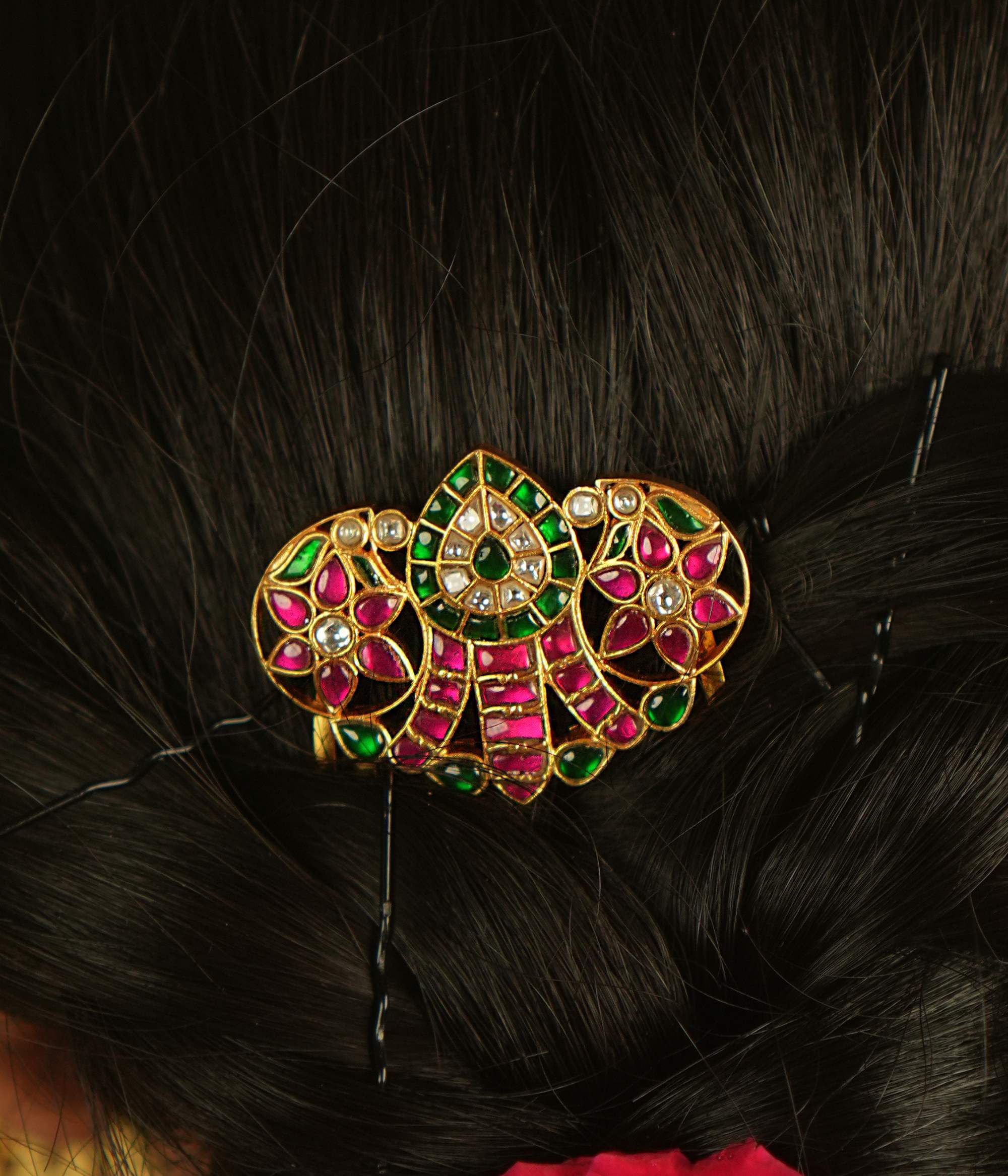 A sleek hairpin featuring a classic mango motif, elegantly embellished with radiant pink and green Kundan, exuding timeless charm.
