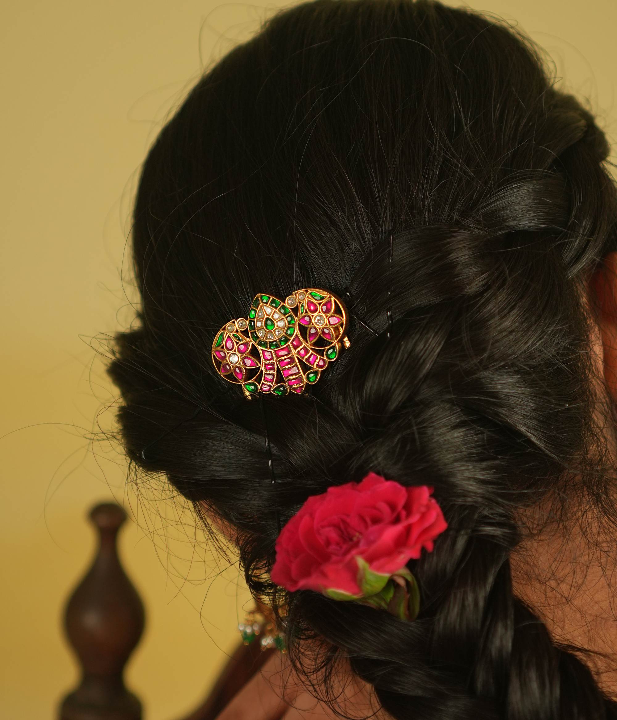 A sleek hairpin featuring a classic mango motif, elegantly embellished with radiant pink and green Kundan, exuding timeless charm.