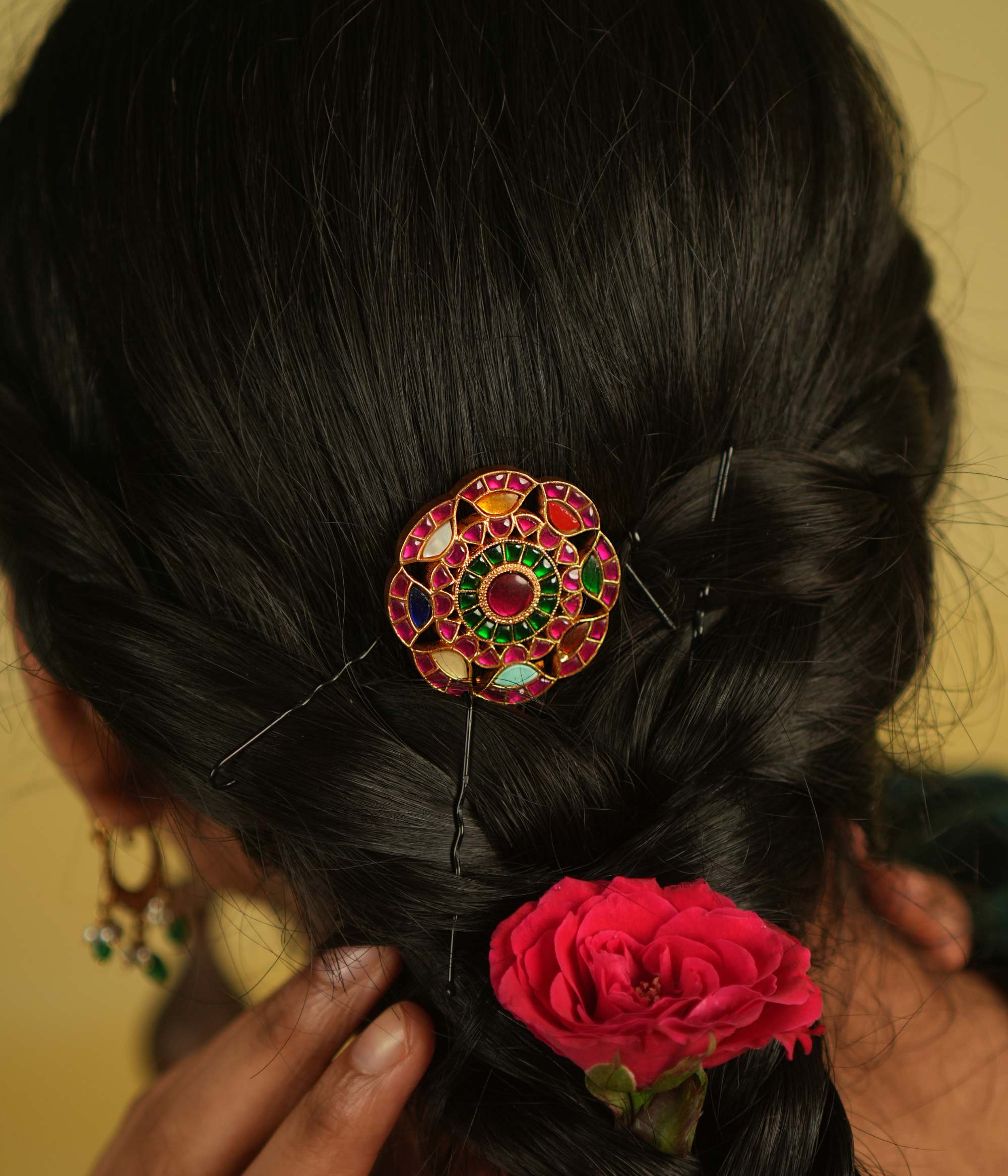 This round-shaped hairpin, adorned with red, white, and green Kundan stones, dazzles with its vibrant hues and intricate craftsmanship, making every moment enchanting.