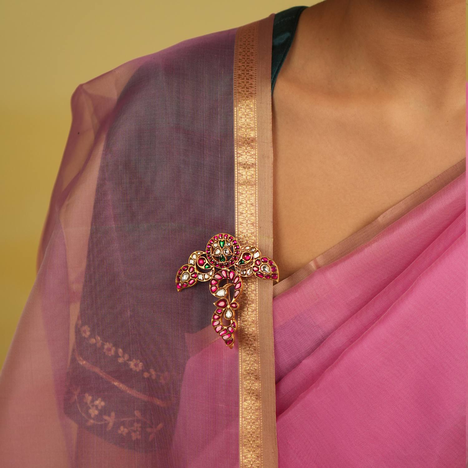A meticulously designed floral saree brooch, embellished with radiant red, green, and white Kundan, exudes timeless regal charm.