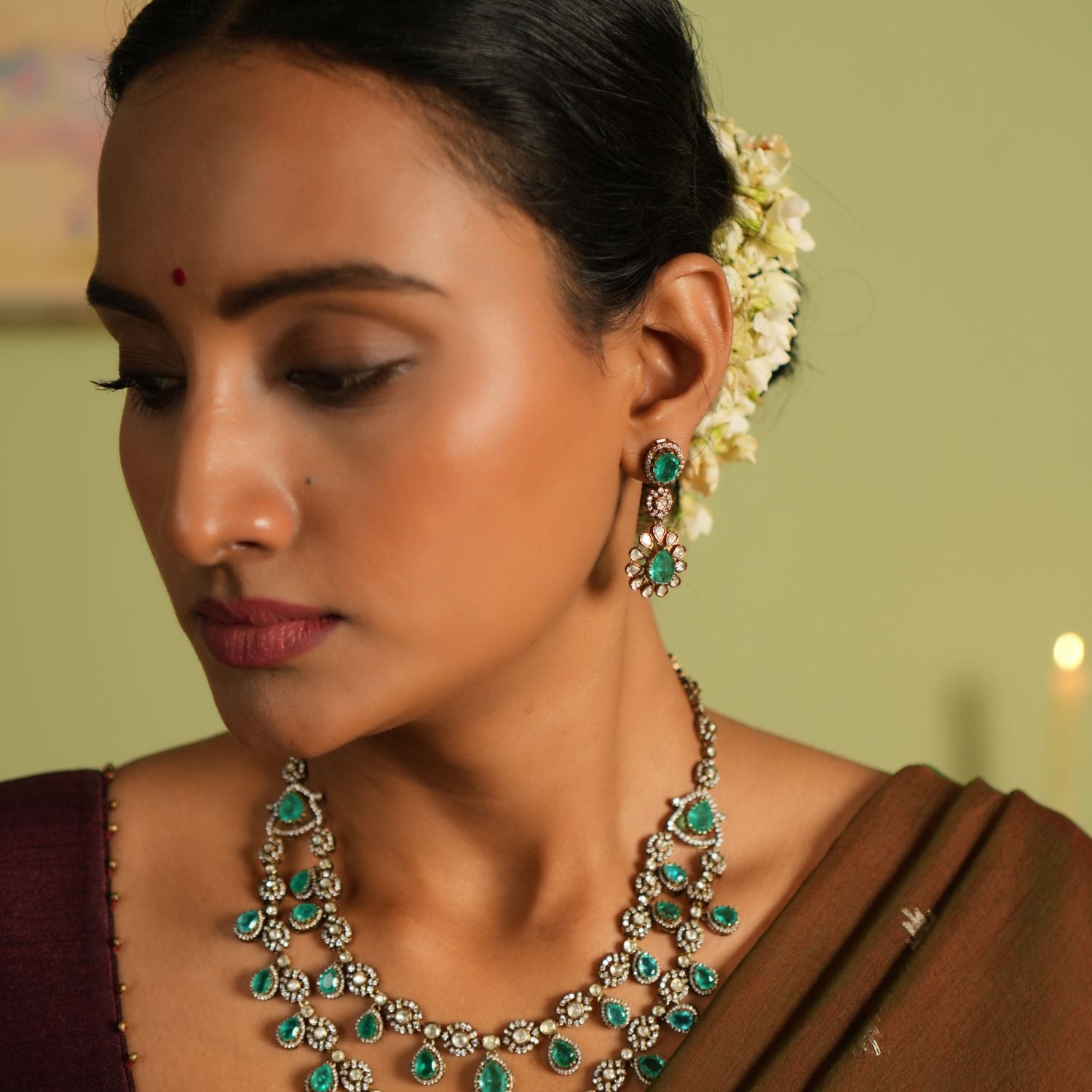 Elegant gold-plated silver drop earrings adorned with moissanite Polki stones, CZ stones, and vibrant green gemstones, and has a flower design offering a timeless and sophisticated design for any occasion.