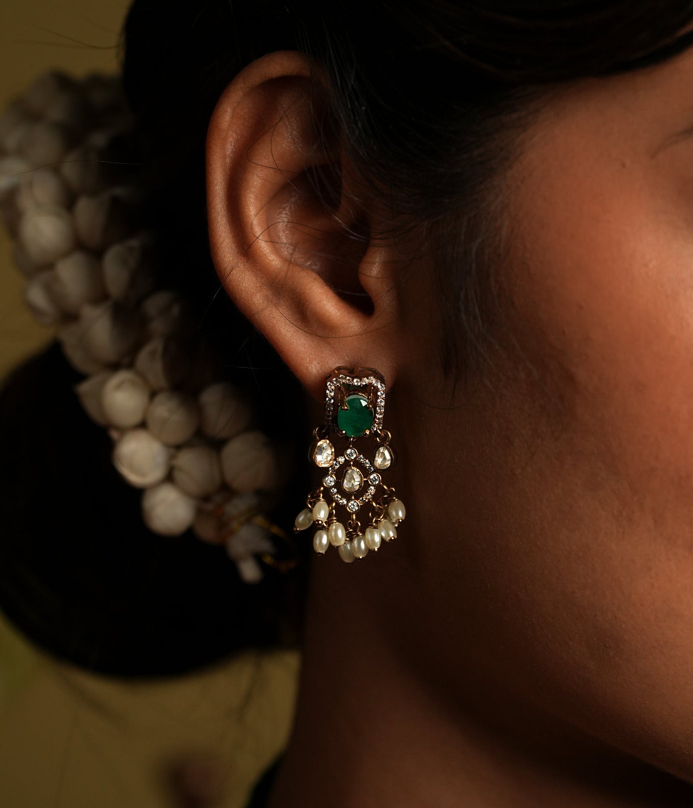 Enhance your traditional look with this exquisite silver gold-plated jewelry set featuring a stunning pair of earrings and a matching necklace. The earrings are intricately designed with green gemstones as the centerpiece, surrounded by shimmering American diamonds and delicate pearl drops for a timeless appeal.