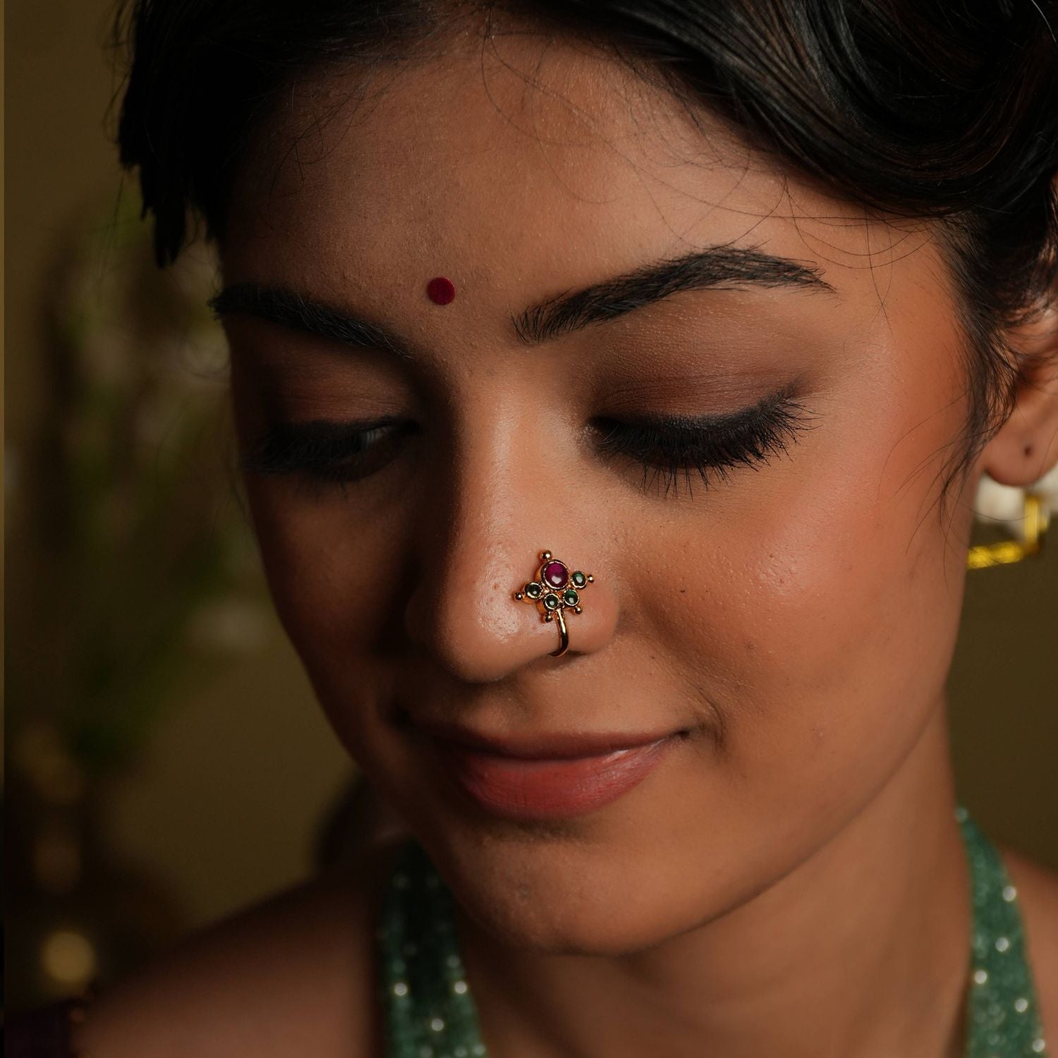 92.5 silver with gold plating Southern blossom, a vintage charm... This minimal floral nose stud shines with delicate
elegance, featuring pink and green Kundan setting. Inspired by vintage Chettinad designs, it evokes the warmth of traditional Indian craftsmanship. A tiny, timeless treasure that adds a touch of subtle sophistication.