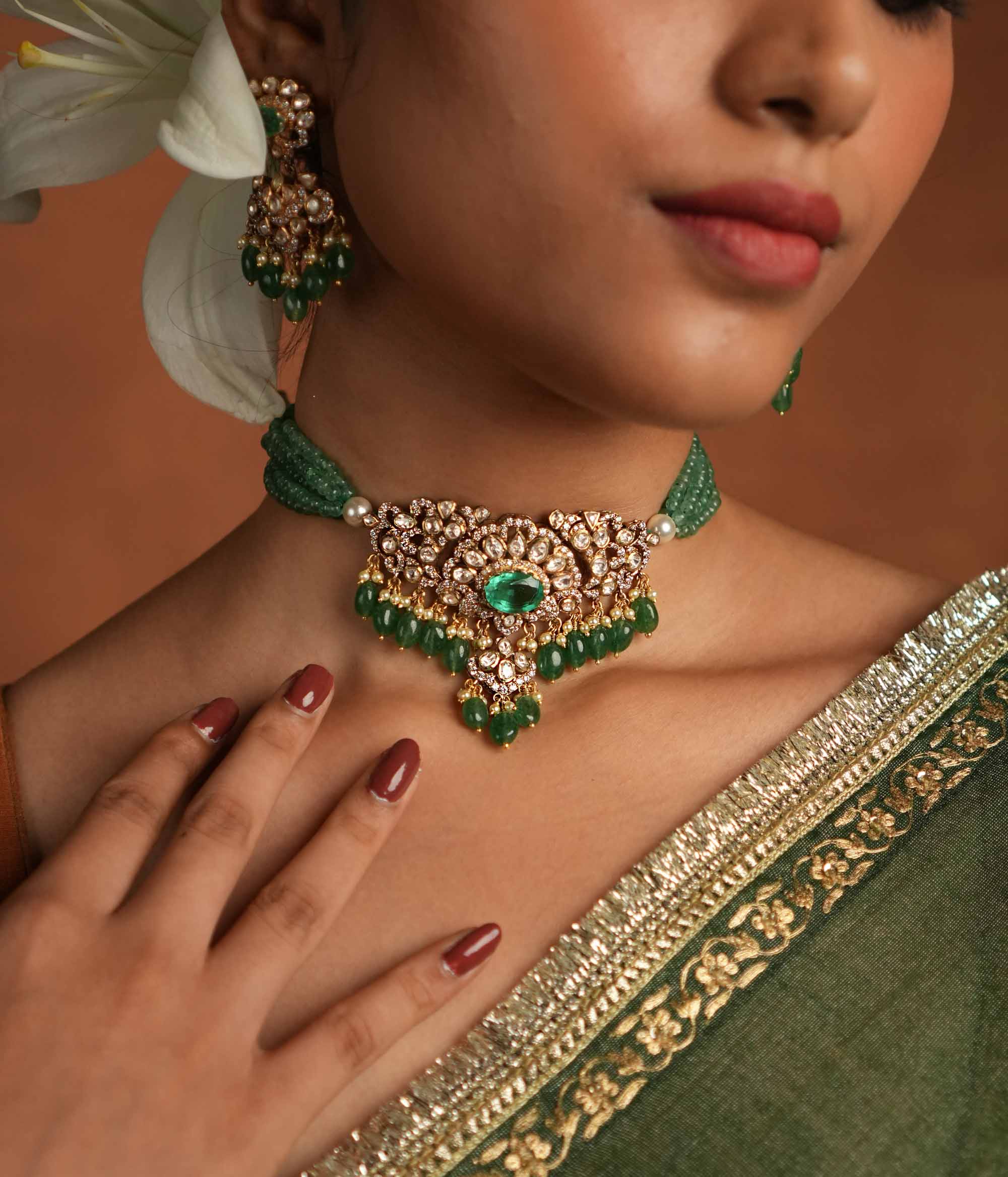 Victorian elegance reborn! This gold-plated silver choker features a striking green gemstone at its heart, surrounded by dazzling polki and CZ stones. Delicate pearl drops with golden beads enhance its timeless allure, whispering tales of a bygone era. A perfect blend of heritage and grace for the modern woman.