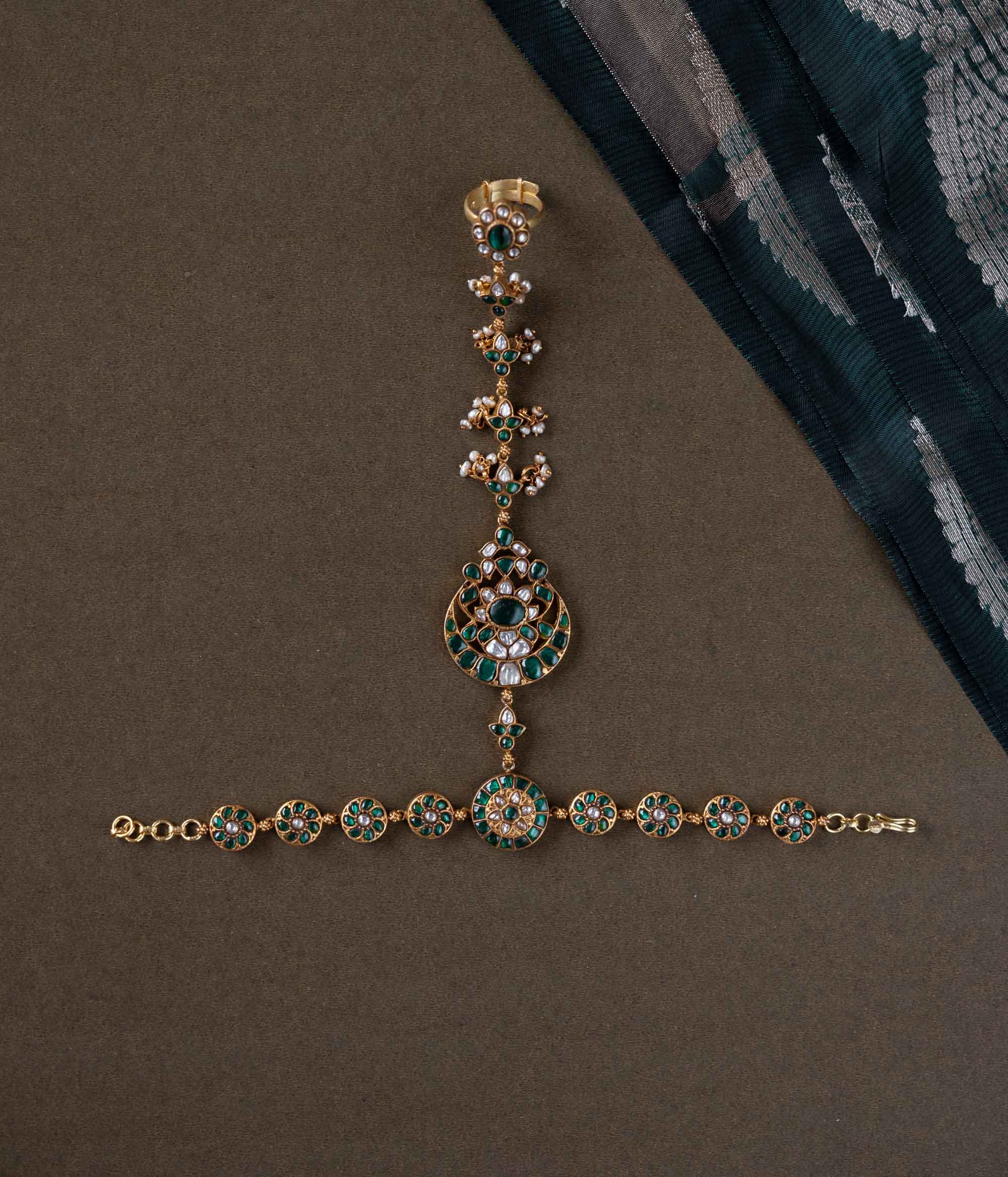 Handmade 92.5 sterling silver and 22ct gold-plated Eshna Emerald Haathphool with white and green Kundan stones, intricate floral motifs, and delicate pearls, exuding royal elegance.
