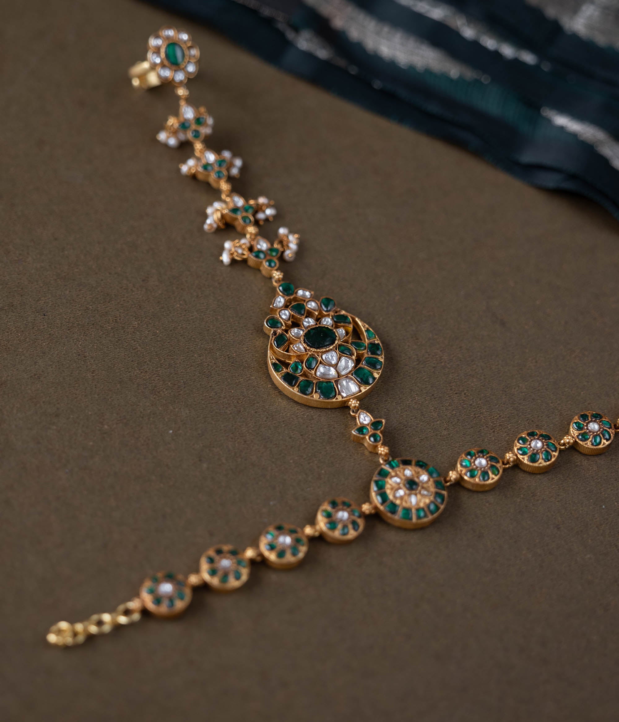 Handmade 92.5 sterling silver and 22ct gold-plated Eshna Emerald Haathphool with white and green Kundan stones, intricate floral motifs, and delicate pearls, exuding royal elegance.