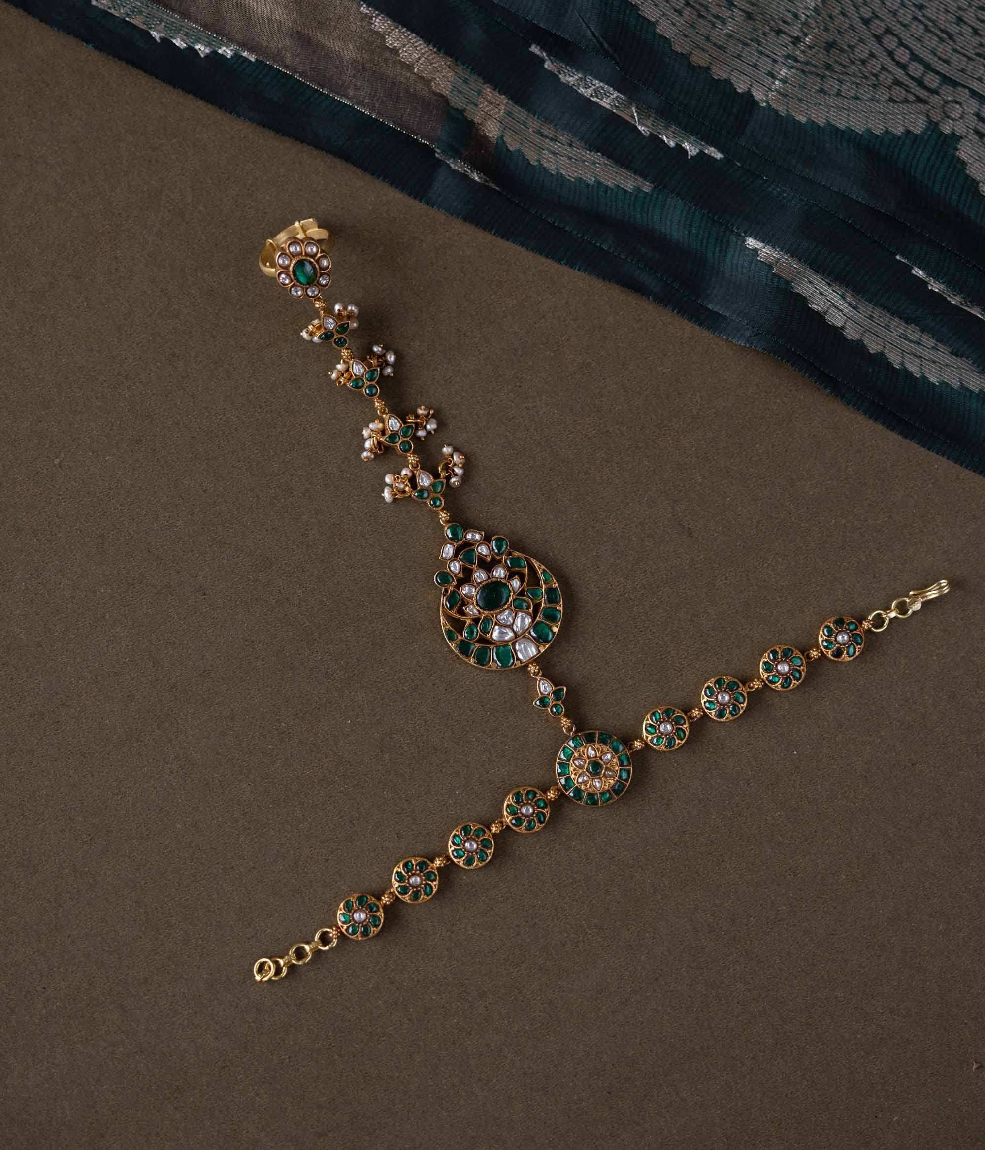Handmade 92.5 sterling silver and 22ct gold-plated Eshna Emerald Haathphool with white and green Kundan stones, intricate floral motifs, and delicate pearls, exuding royal elegance.